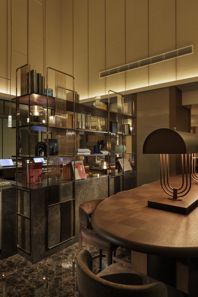 Art Deco-style restaurant interior with red cushioned booths, geometric metal dividers, warm lighting, and blue glassware. Elegant and inviting ambiance.