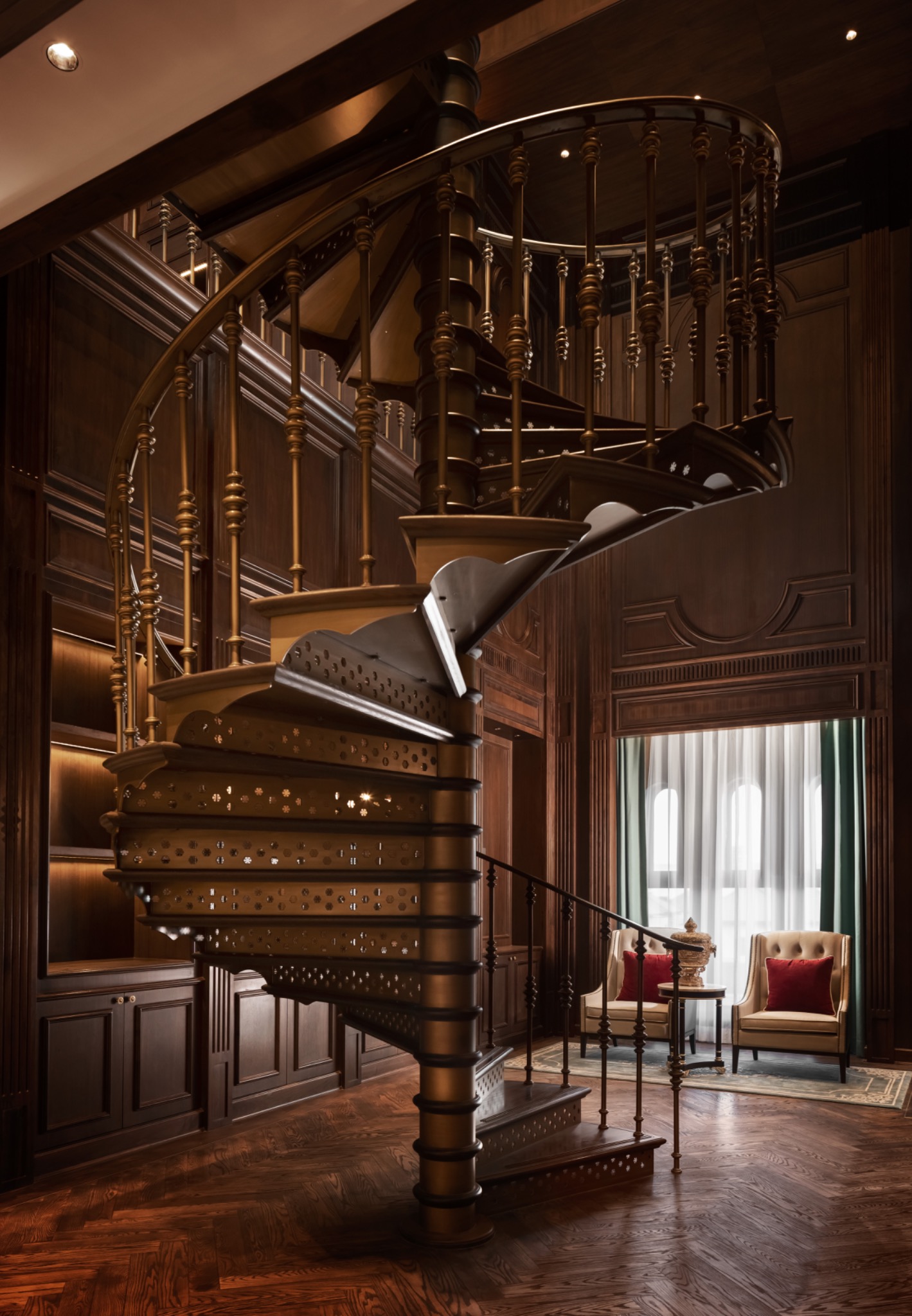 Elegant wooden spiral staircase in a luxurious library with rich dark wood paneling. Soft lighting creates a warm, inviting atmosphere; plush chairs by a window.