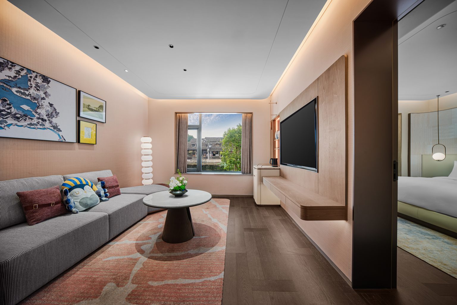 Modern living room with a large window view, featuring a gray sofa, coffee table, and built-in shelf, creating a cozy ambiance.
