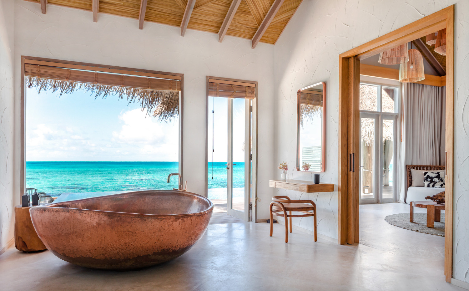 A copper bath in a Maldivian style bathroom of an overwater bungalow style hotel room.