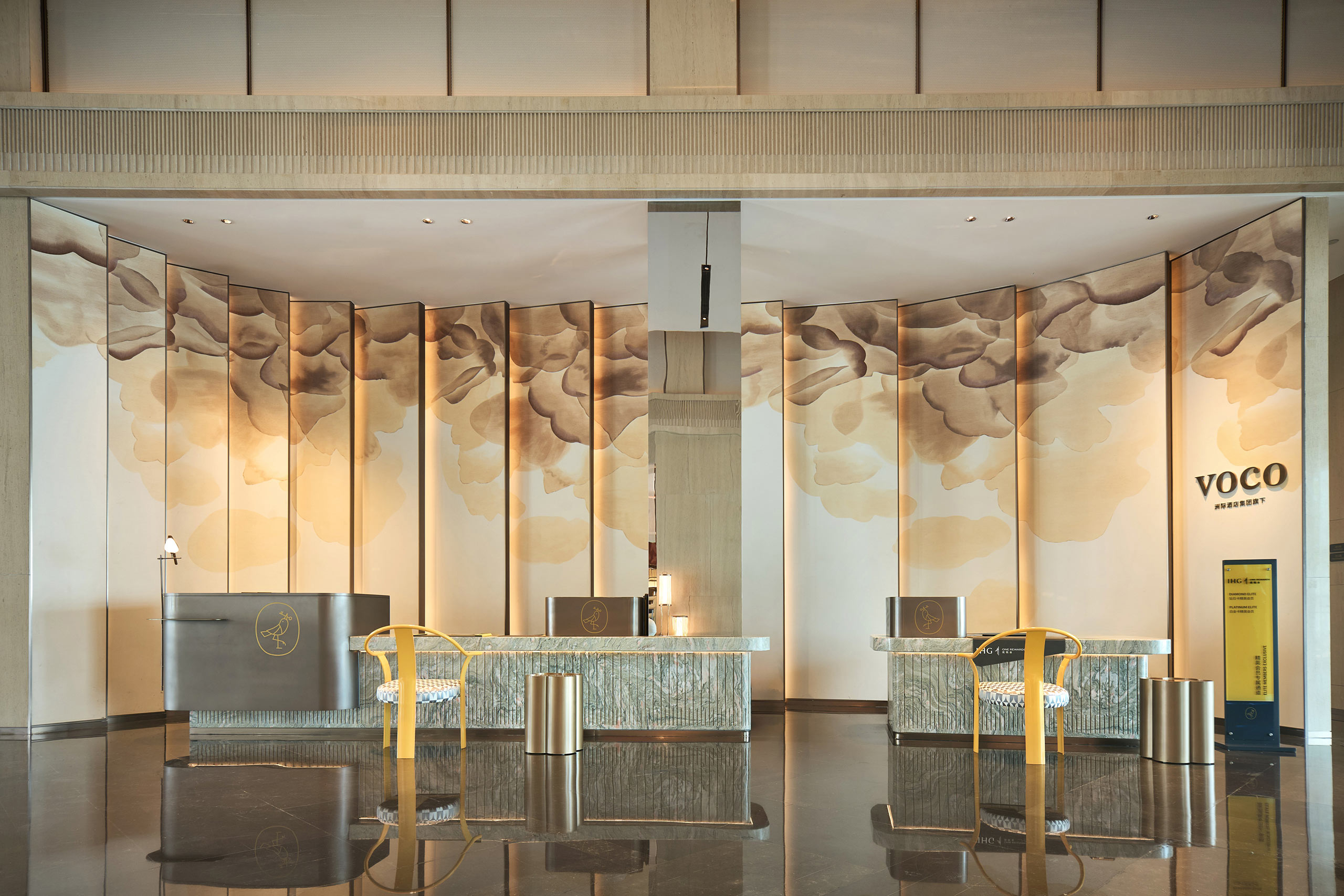 Luxurious hotel lobby with elegant reception desks, gold accents, and cloud-patterned wall decor. The ambiance is warm and inviting, exuding sophistication.