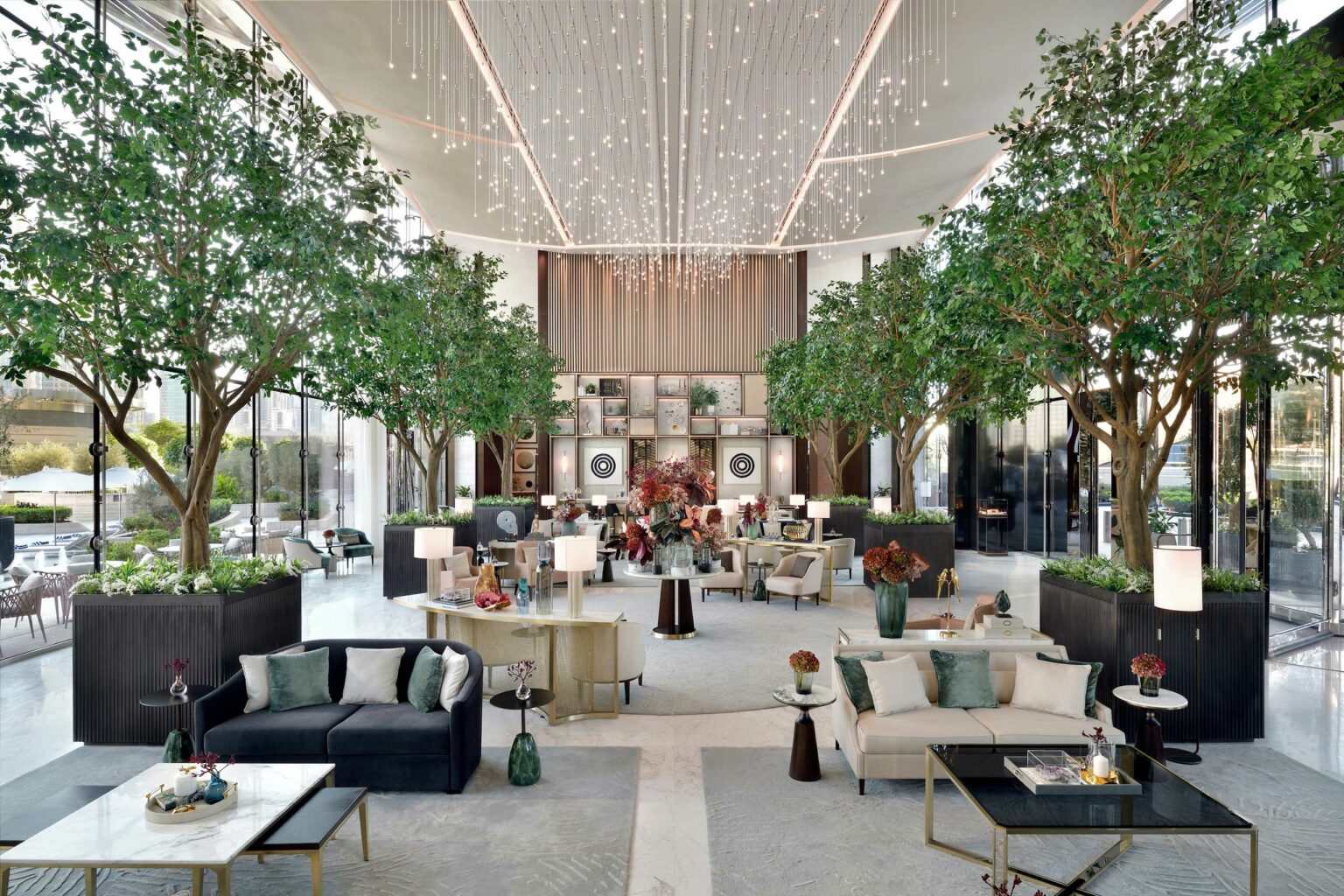 Luxurious hotel lobby with high ceiling and string lights. Features elegant sofas, coffee tables, and potted trees. Airy and sophisticated ambiance.