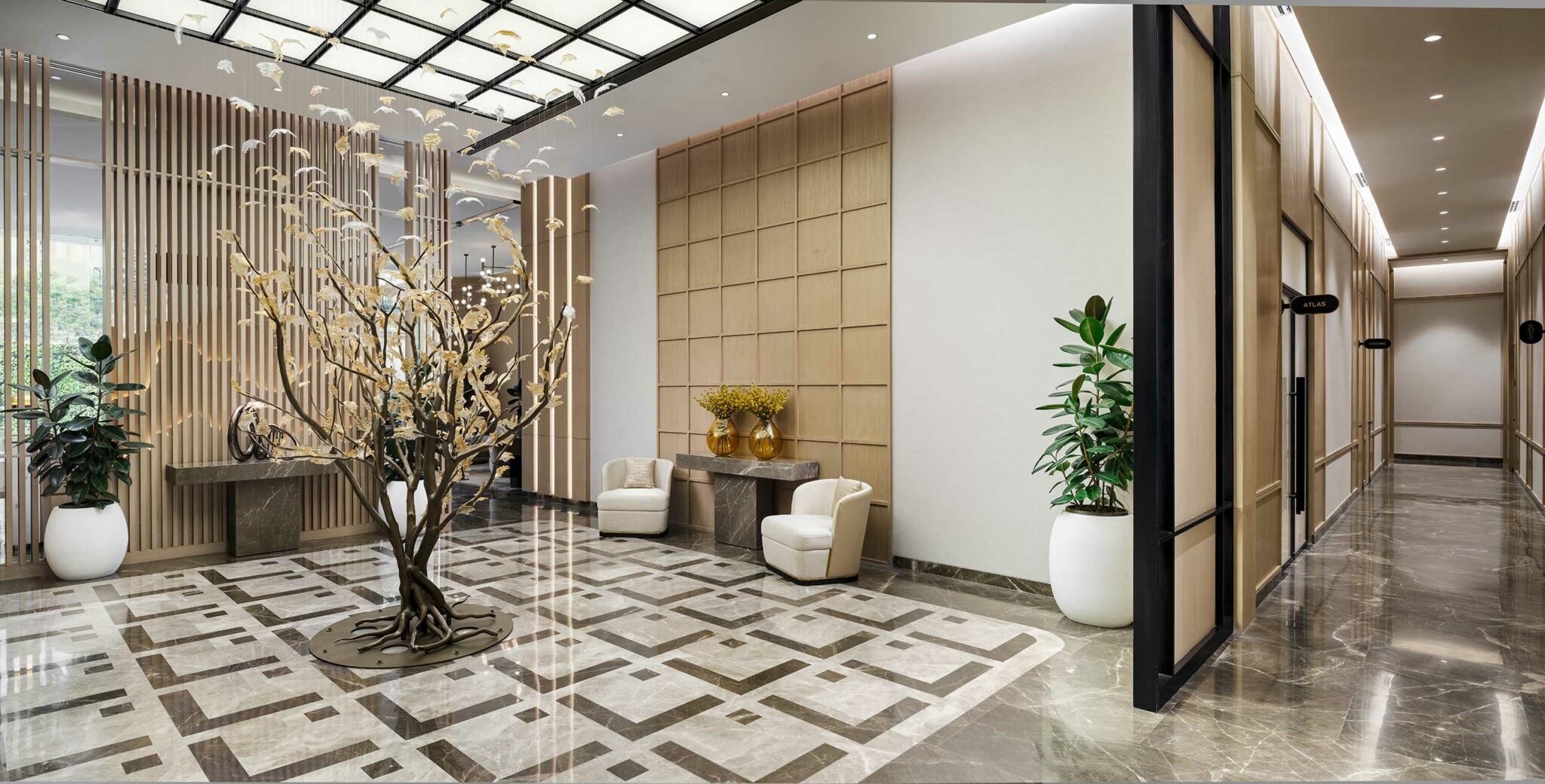 Spacious, modern office lobby with marble floor, wooden panels, large abstract tree sculpture at center. Minimalist furniture and potted plants add elegance.
