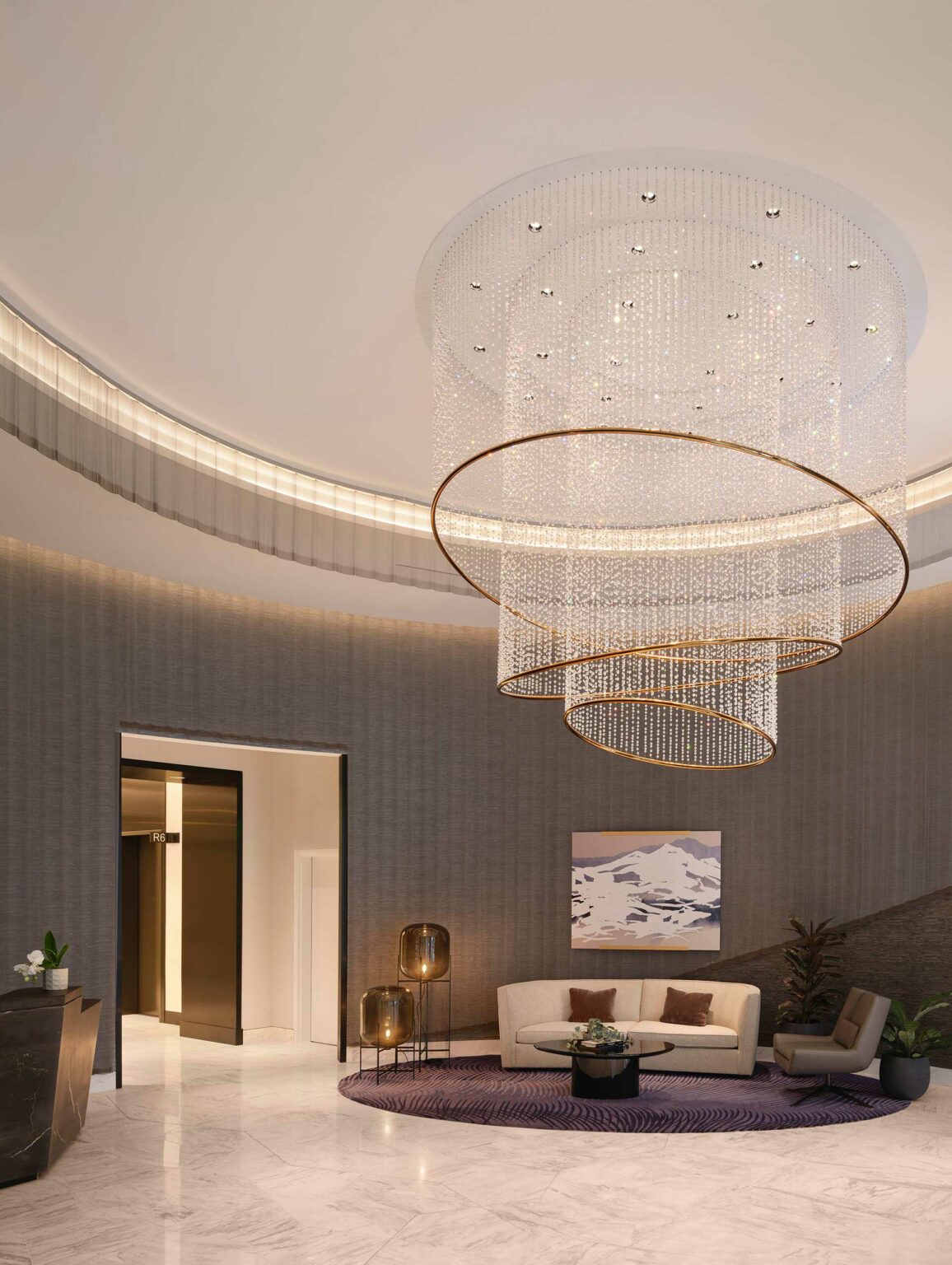 Luxurious hotel lobby with an elegant circular chandelier, modern furniture, and soft lighting. A purple rug and abstract art add sophistication.