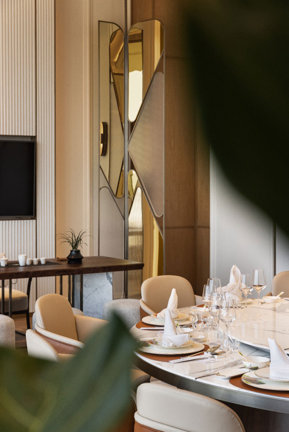 Elegant hotel dining room with beige chairs around a round table set with white napkins, glasses, and plates. Modern decor with a stylish wall mirror.