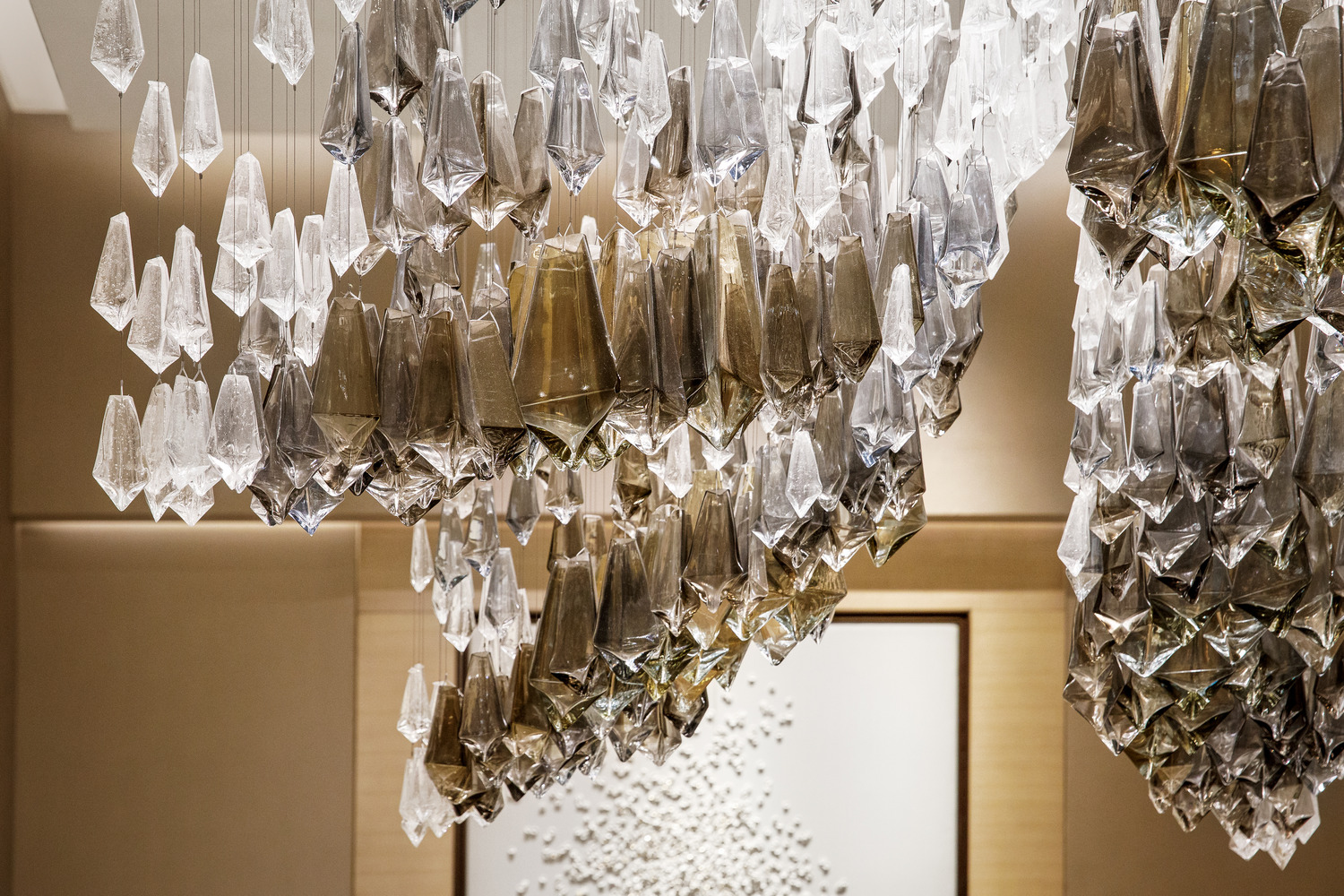 A stunning chandelier composed of intricate glass crystals, elegantly suspended from the ceiling, reflecting light beautifully and adding a touch of sophistication to the modern and luxurious interior space.