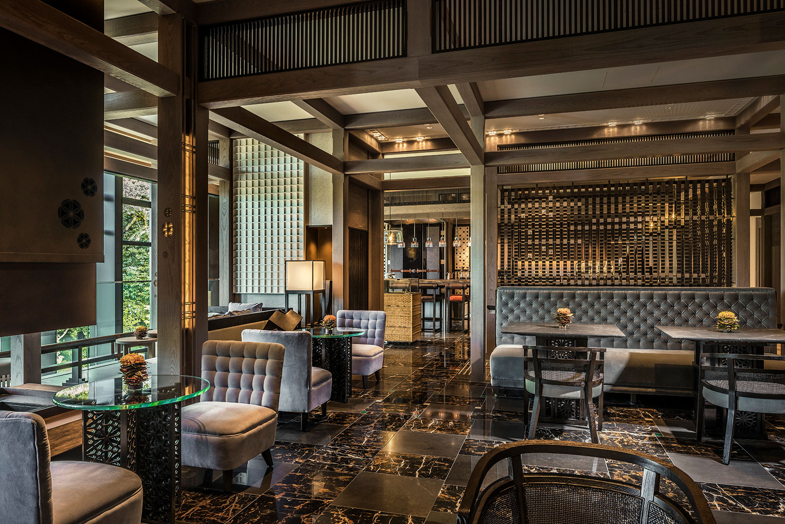 Luxurious hotel lounge with plush seating, glass tables, and soft lighting. Dark marble floors and wooden accents create a sophisticated, cozy atmosphere.