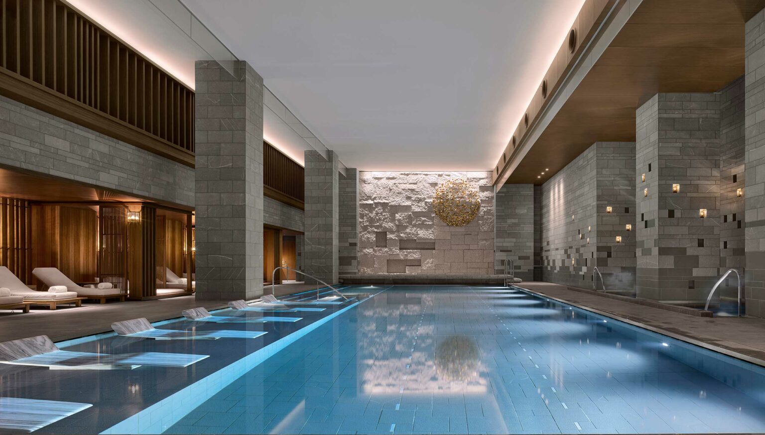 Luxurious indoor hotel pool with sleek stone walls, ambient lighting, and modern lounge chairs. Calm, sophisticated atmosphere with a serene water reflection.