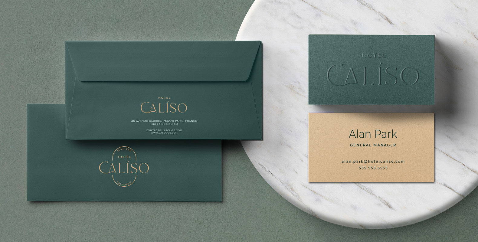 Dark green stationery set for Hotel Caliso, featuring elegant envelopes and business cards on a marble surface. The tone is sophisticated and formal.