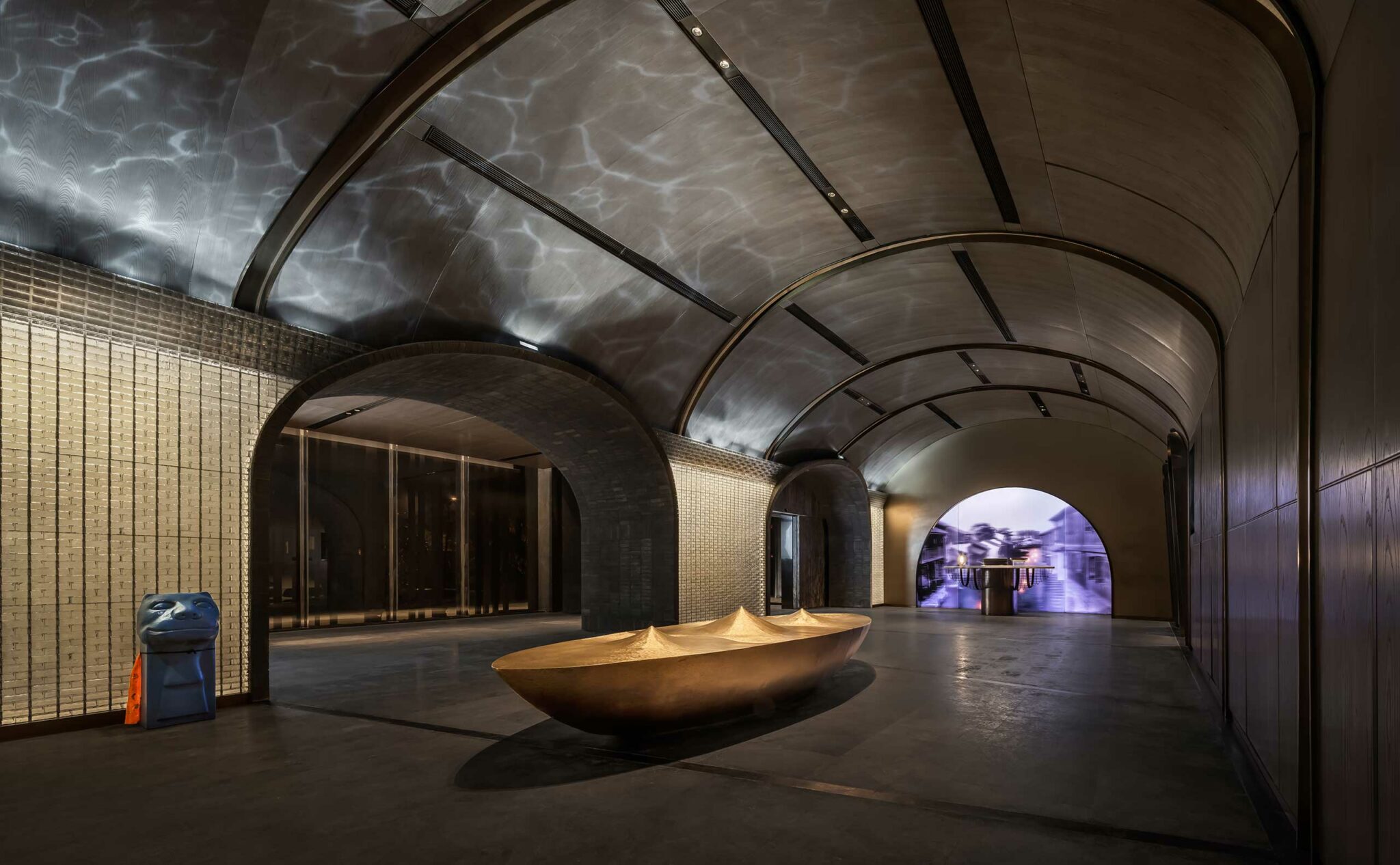 Modern hotel hallway with arched ceilings, soft lighting, and a reflective art installation resembling a boat. The tone is serene and elegant.
