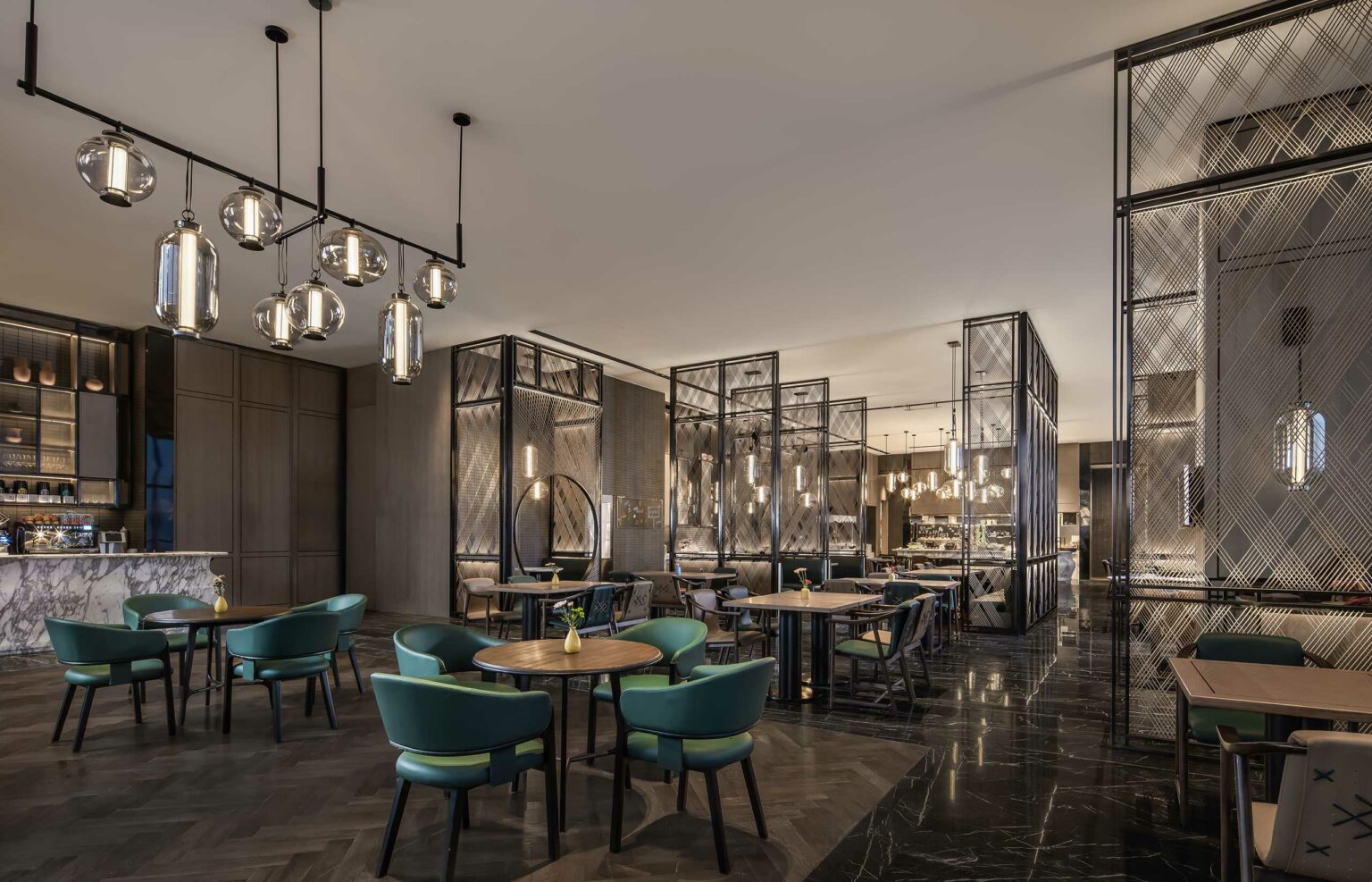 Modern chic hotel restaurant interior with teal chairs, wooden tables, and elegant hanging lights. Black metal partitions create a stylish, cozy atmosphere.