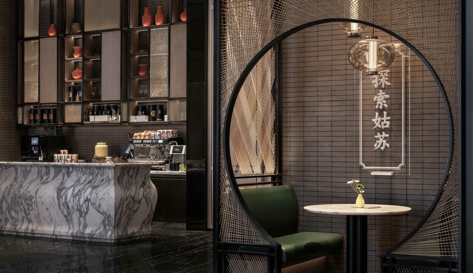 Sleek hotel restaurant nook with marble counter, minimalist shelves displaying decorative items, a small round table with a green chair, and soft lighting creating a cozy atmosphere.