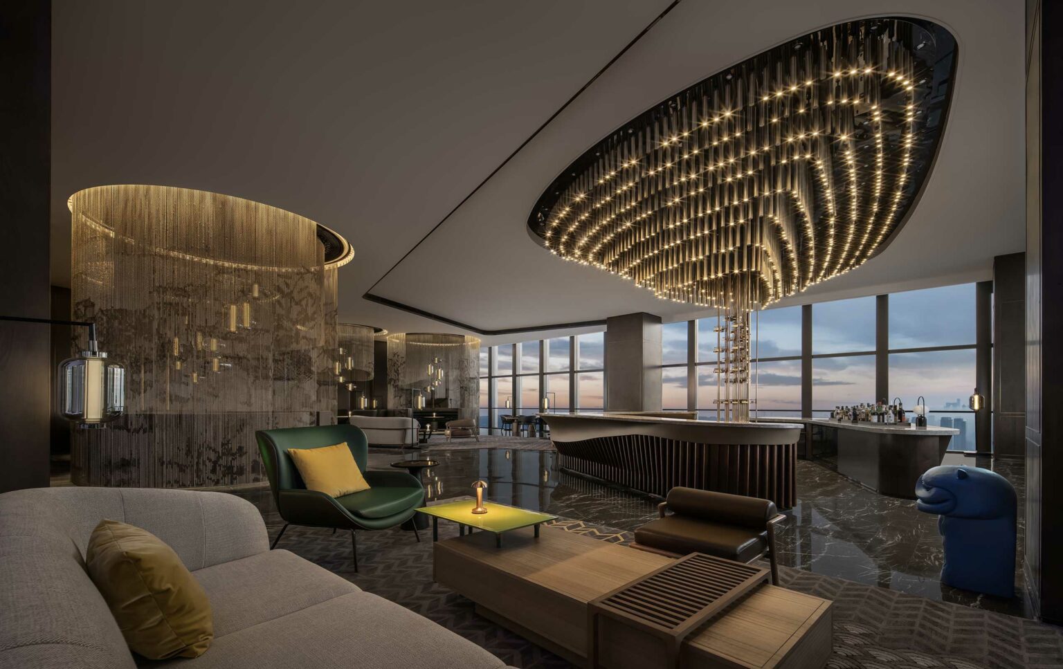 Luxurious modern hotel lobby with dim lighting and a large, elegant chandelier. Features sleek furniture, a plush sofa, and panoramic city views.
