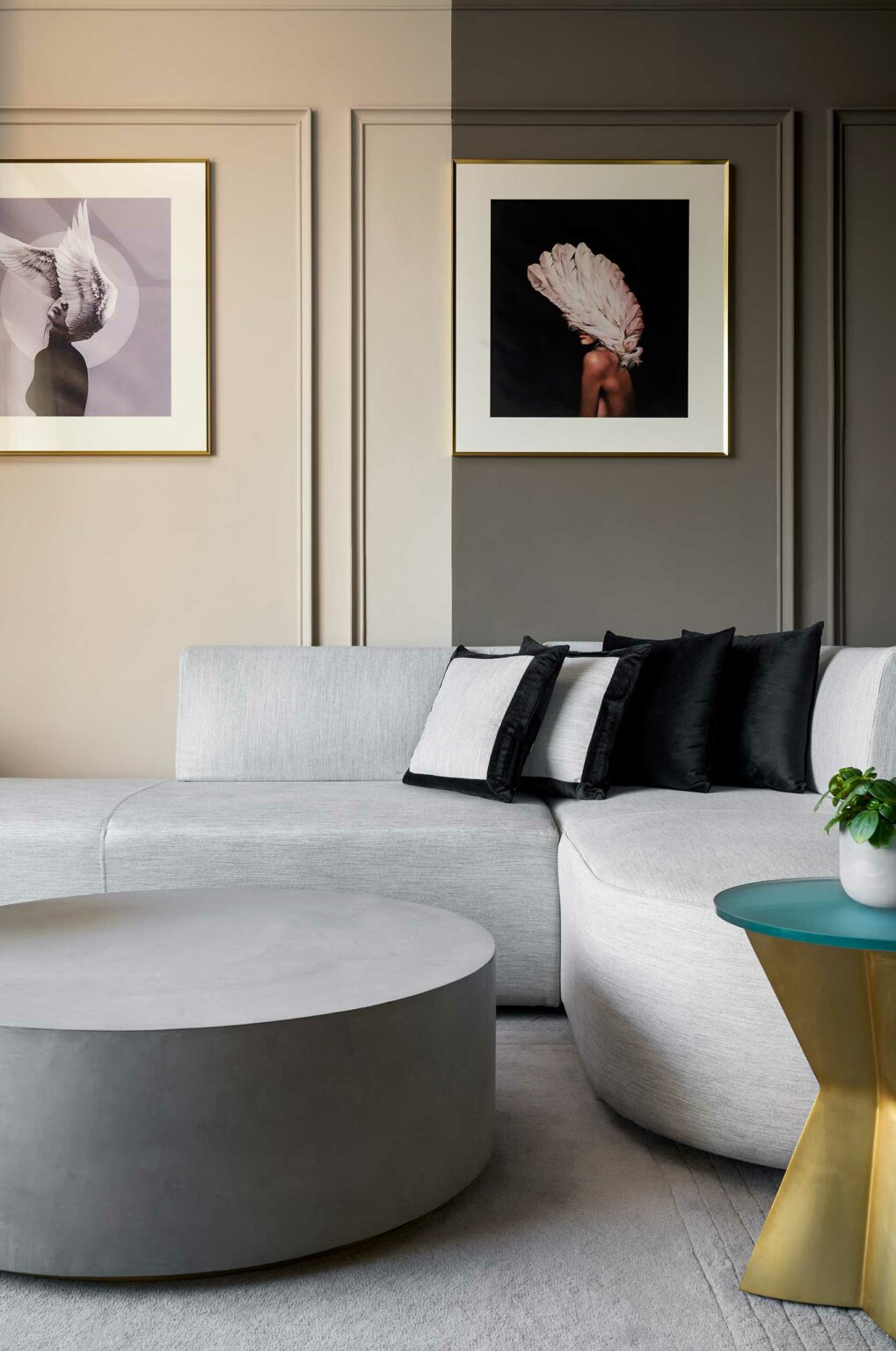 Sophisticated suite living room with a gray sectional sofa, black and white pillows, two pieces of abstract feather art, and a round coffee table.