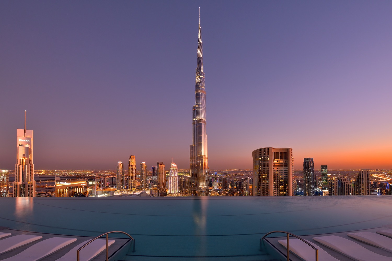 A stunning skyline view at sunset featuring the Burj Khalifa, with a luxurious infinity pool in the foreground, creating a breathtaking scene of Dubai's vibrant cityscape and twilight hues.