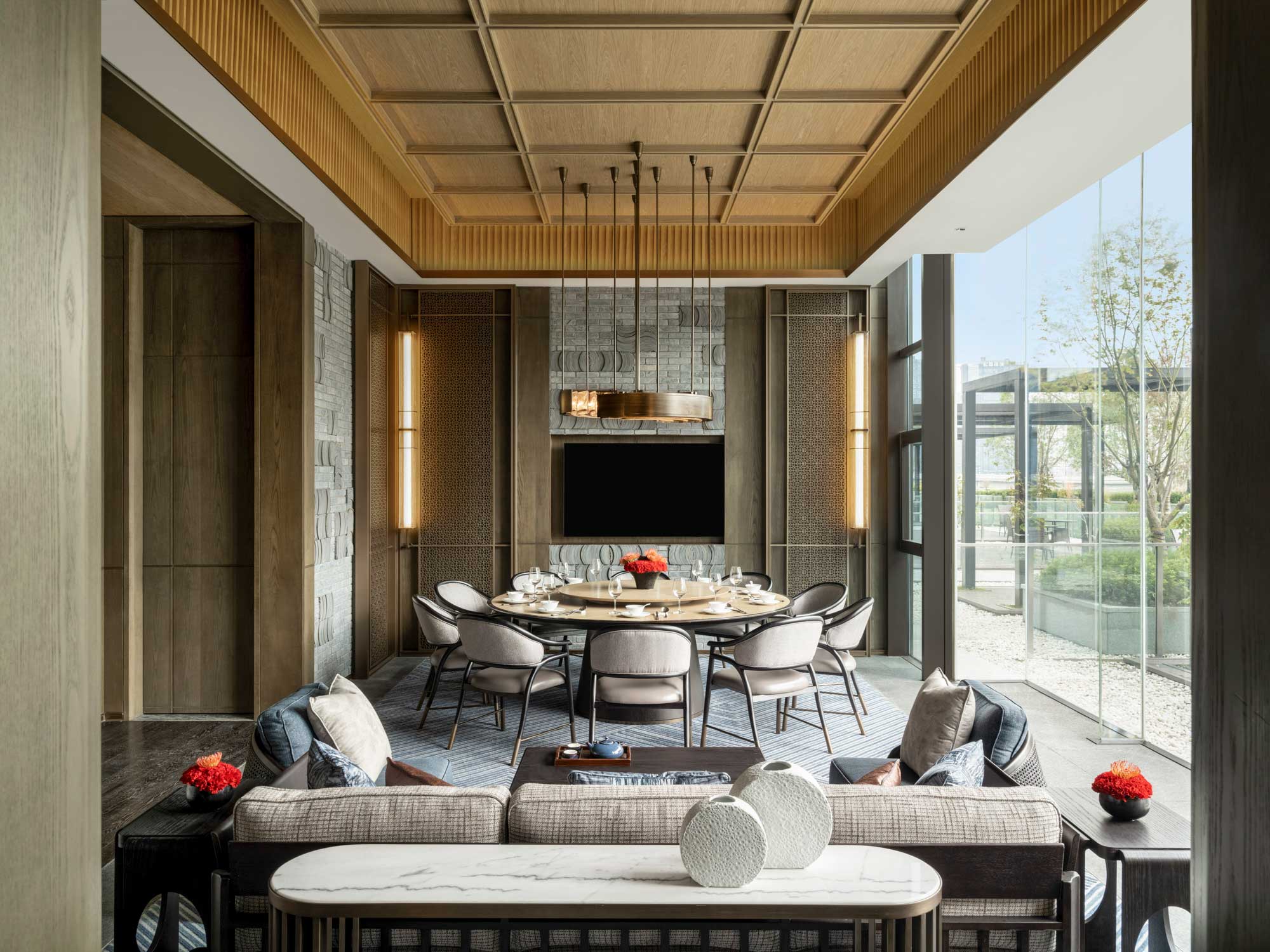 Luxurious suite dining room with round table, plush chairs, and a modern chandelier. Large windows offer natural light, complementing the elegant decor.