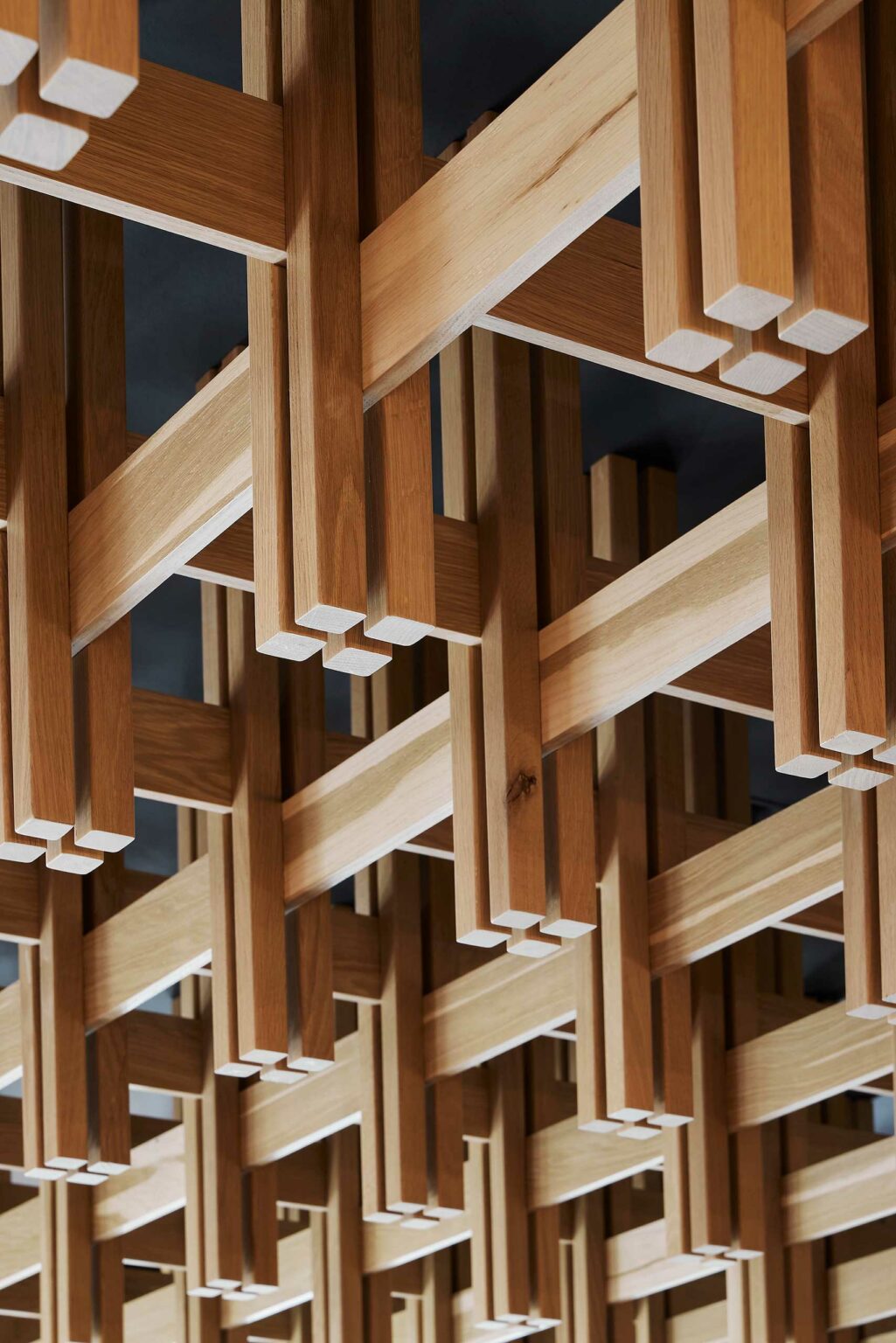 Intricate wooden lattice with intersecting beams creates a geometric pattern, conveying a sense of complexity and craftsmanship against a dark background.