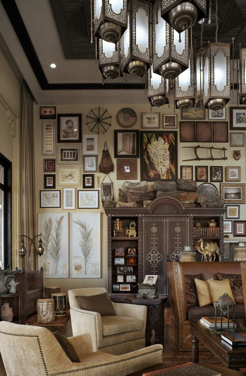 Stylish suite living room with an eclectic mix of framed art covering the walls, vintage decor, and ornate hanging lanterns, creating a cozy, curated ambiance.