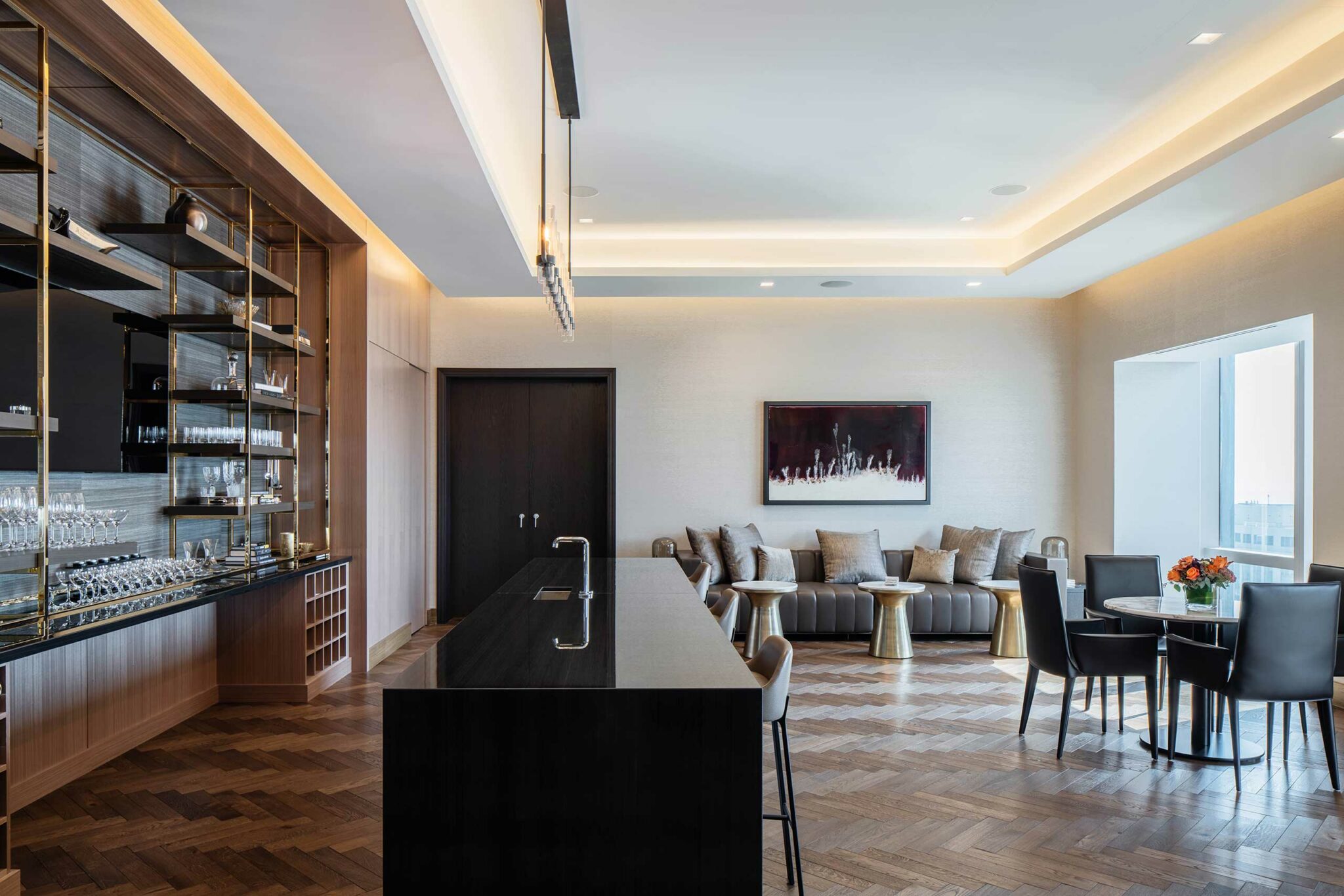 Sleek, modern lounge with a black countertop bar, wooden shelves, and a cozy sitting area. Soft lighting creates a warm, inviting ambiance.