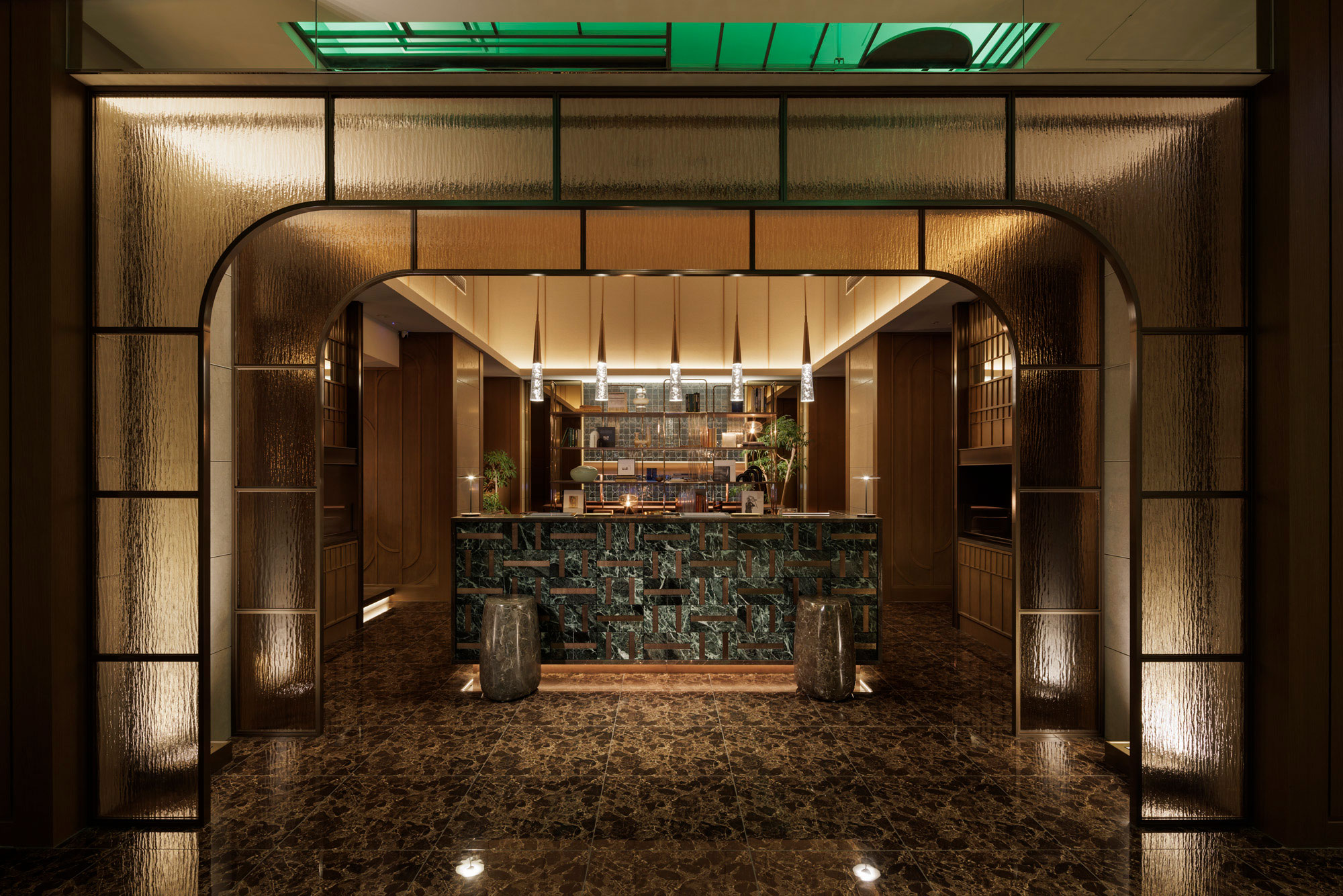 Elegant hotel bar interior with a marble counter surrounded by warm wood panels and soft lighting. Art Deco-style archway adds a sophisticated touch.