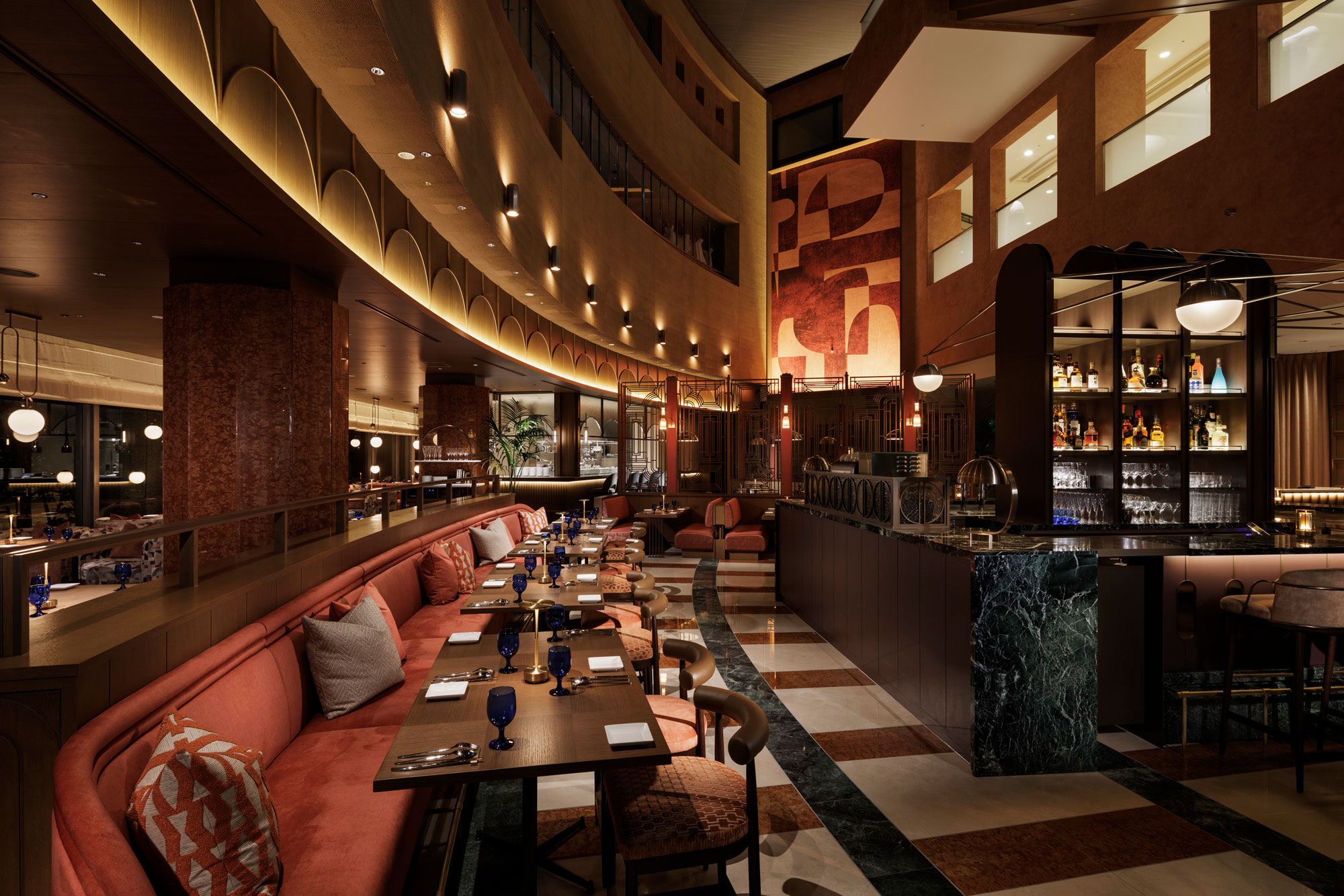 Luxurious restaurant interior with curved seating, elegant lighting, and an upscale bar. Warm tones create a sophisticated and inviting atmosphere.