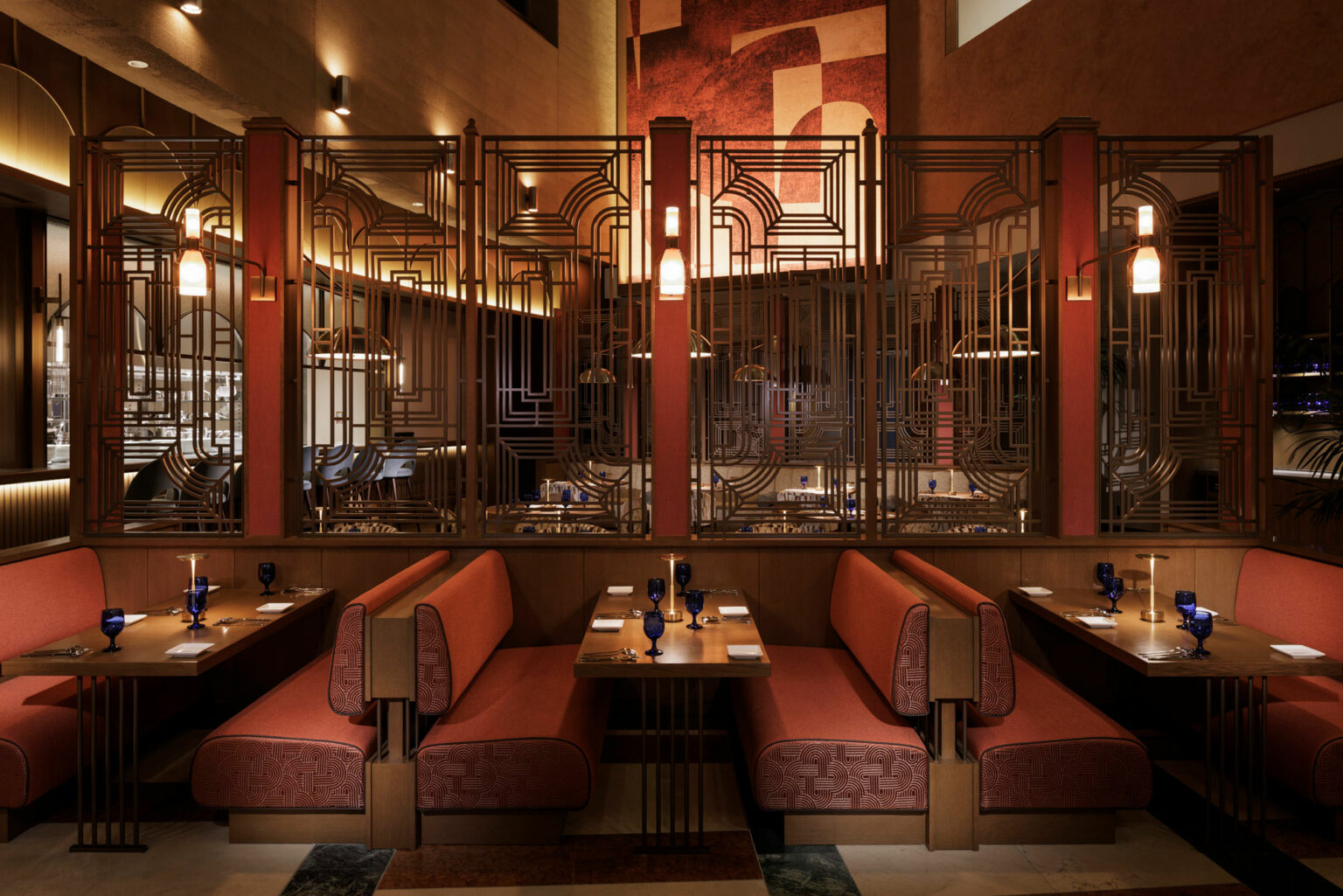 Art Deco-style restaurant interior with red cushioned booths, geometric metal dividers, warm lighting, and blue glassware. Elegant and inviting ambiance.