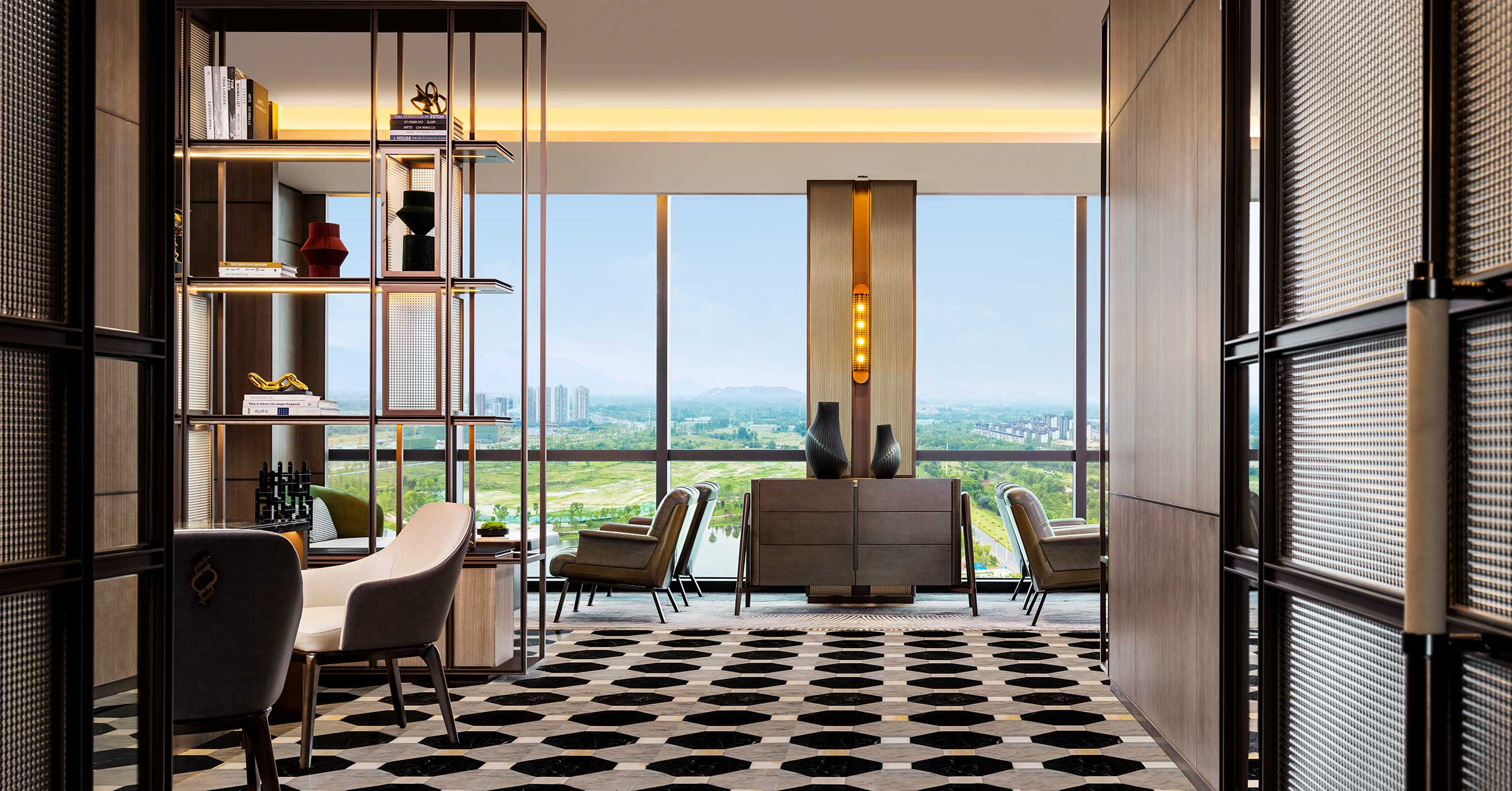 Sophisticated hotel lounge with modern furniture, large window offering a cityscape view, geometric patterned floor, and warm ambient lighting.