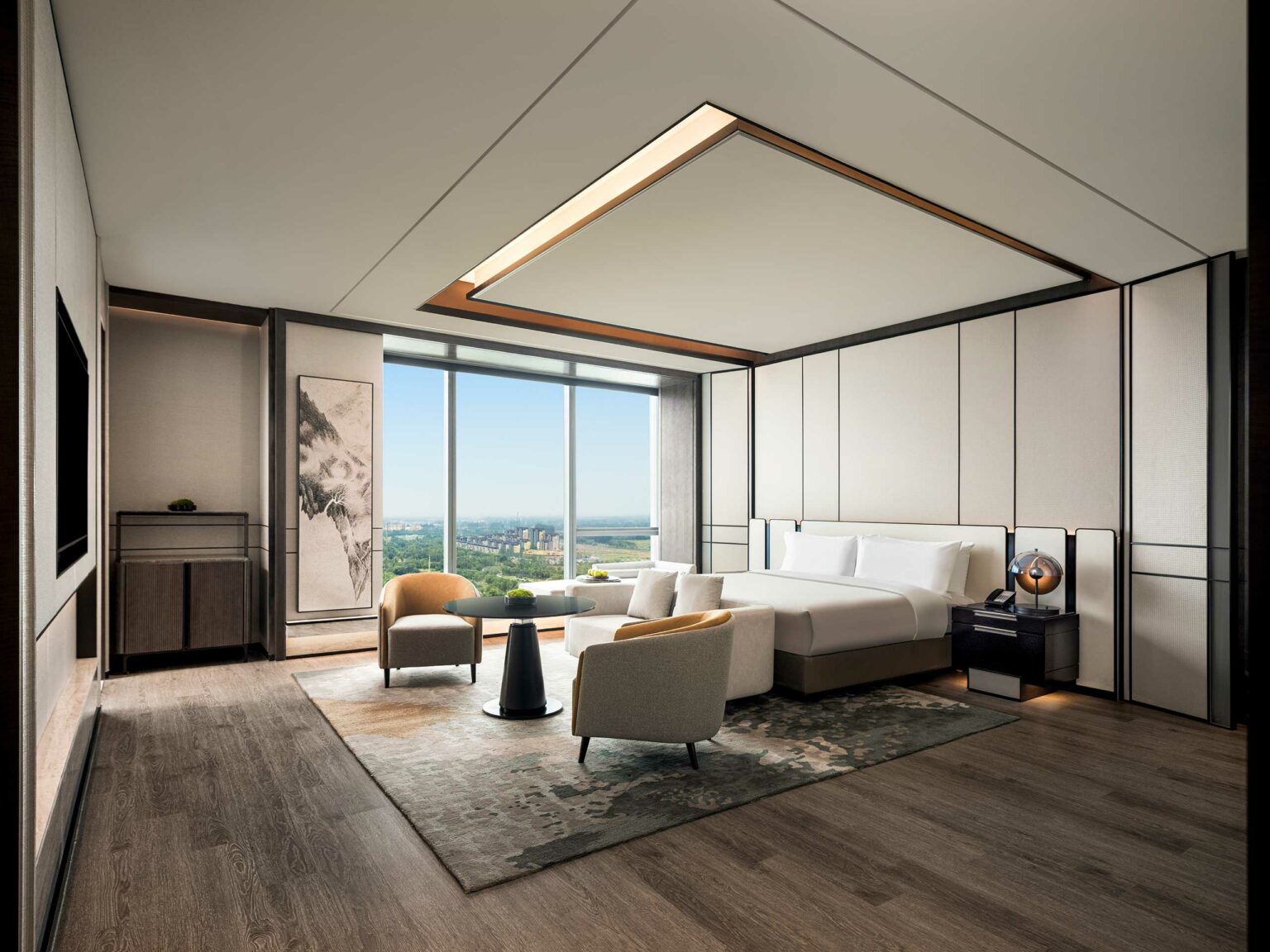 Modern hotel room with large windows showcasing a city view. Features a king bed, elegant seating area, light wood flooring, and a serene ambiance.