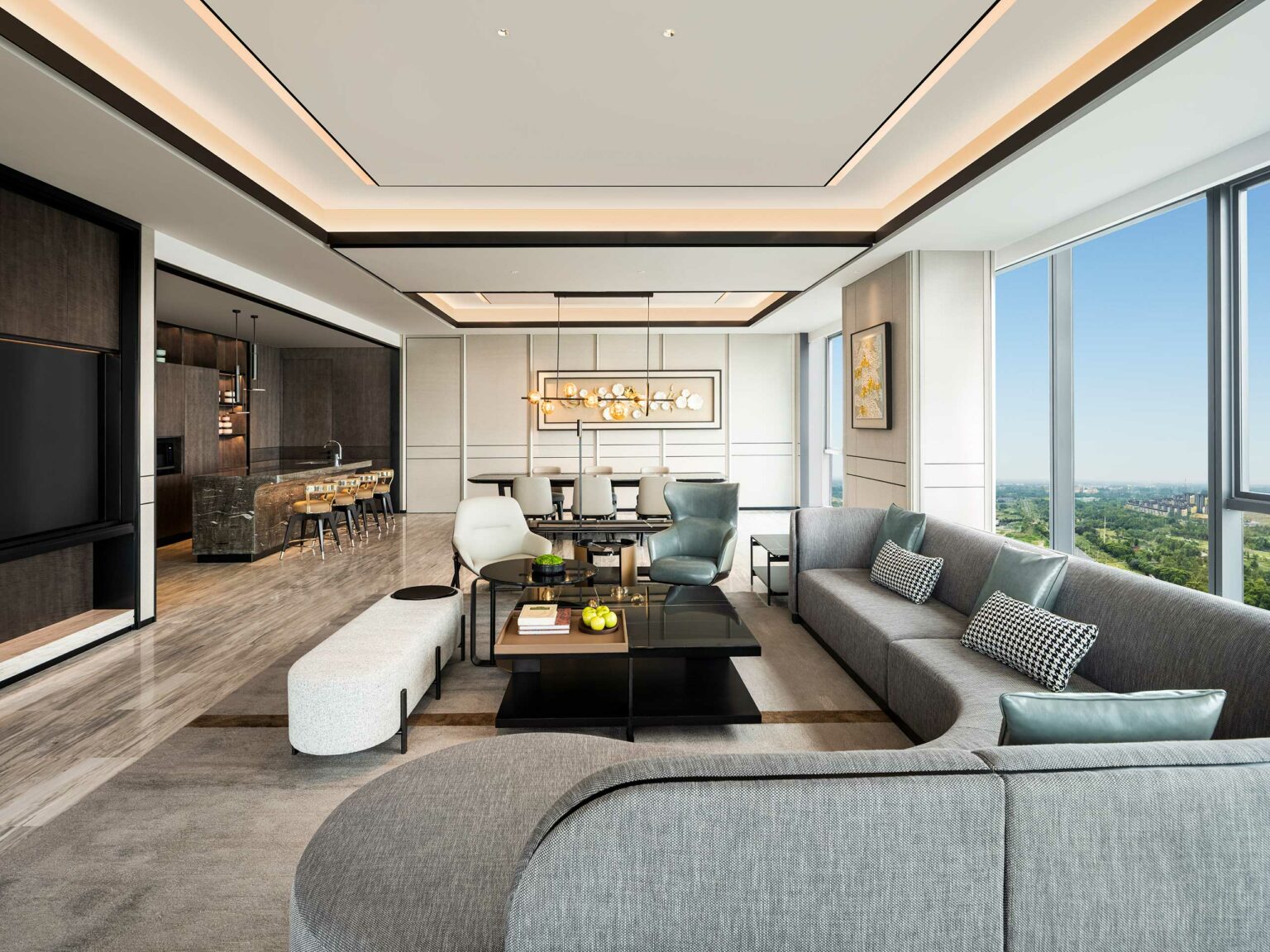 Luxurious modern living room with sleek gray sectional sofa, light-filled dining area, and city views. Features elegant decor and contemporary lighting.
