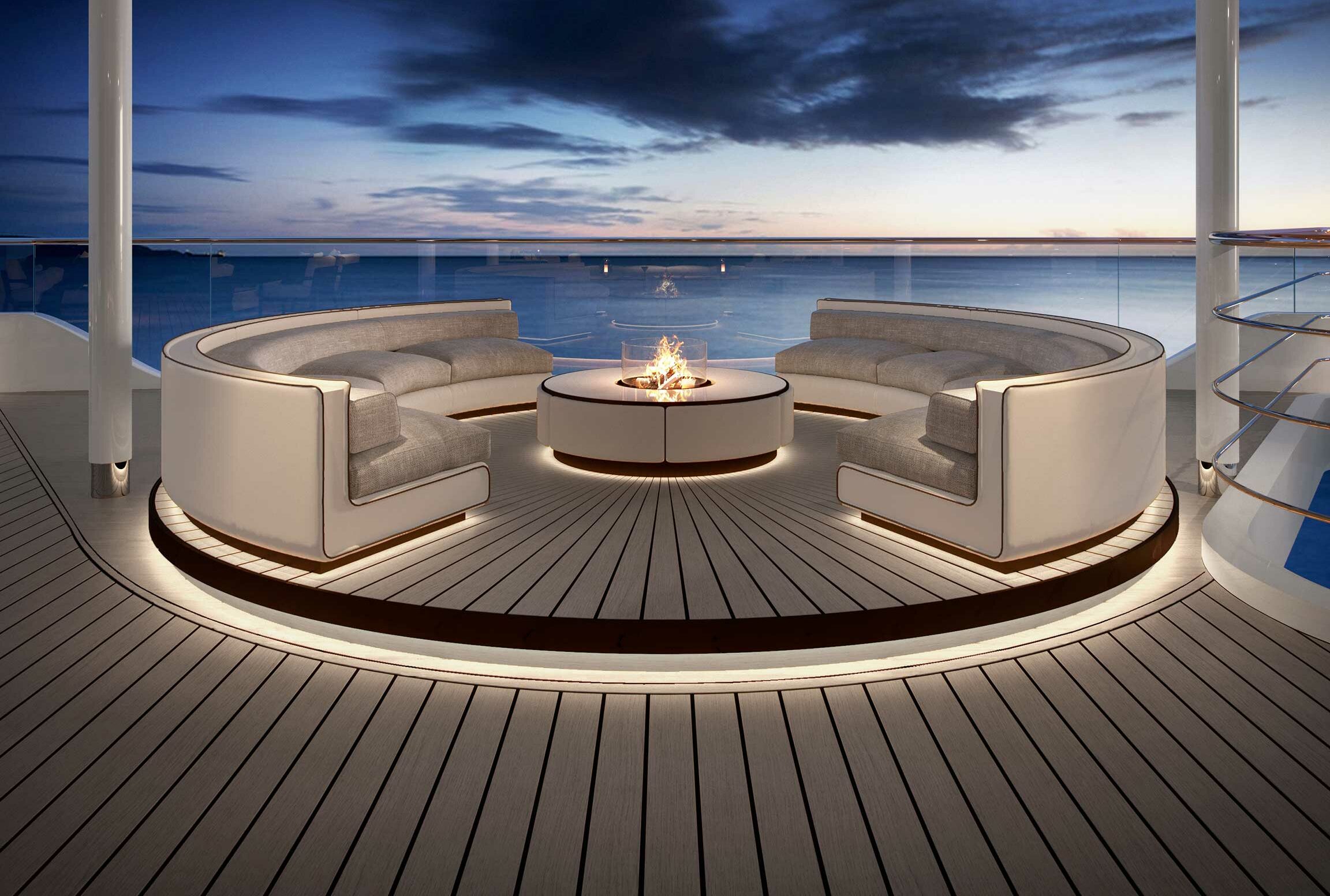 Luxurious cruise deck with curved sofas around a circular fire pit. Tranquil ocean and dramatic twilight sky create a serene and elegant ambiance.