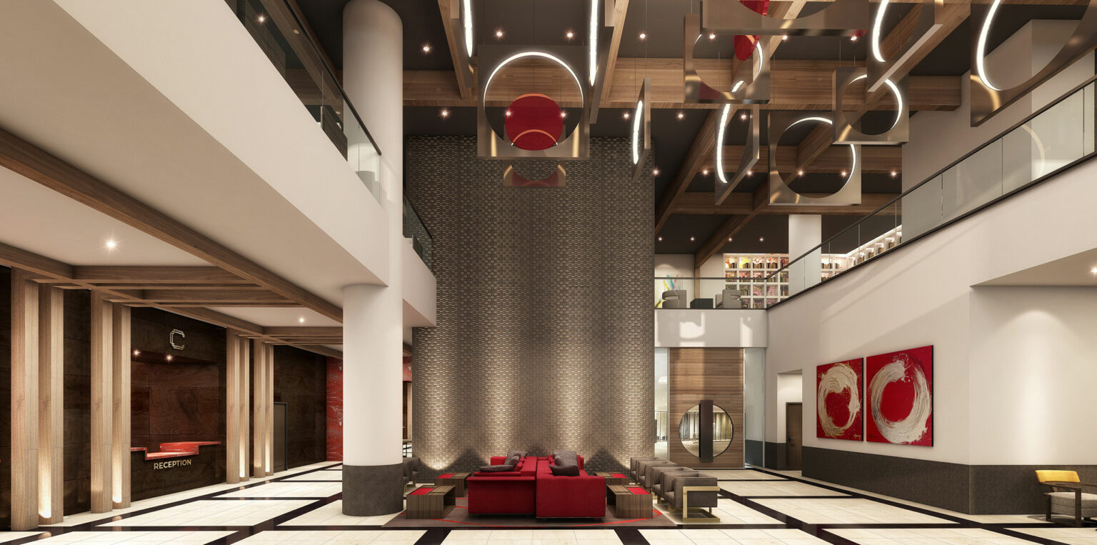 Modern hotel lobby with high ceilings, featuring a stylish chandelier, red and beige seating, and art on walls. The space feels luxurious and inviting.