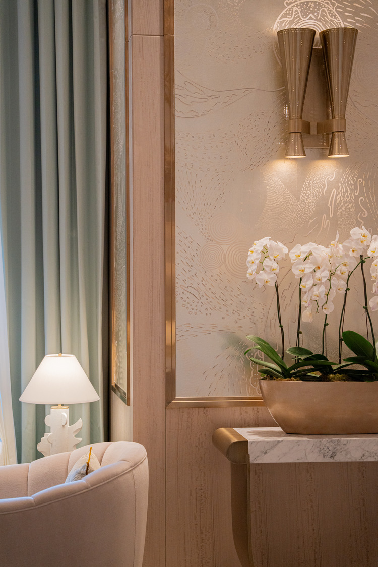 Luxurious hotel lobby with ornate, cascading chandelier and soft lighting. Elegant armchairs line the walls, creating a welcoming, sophisticated atmosphere.