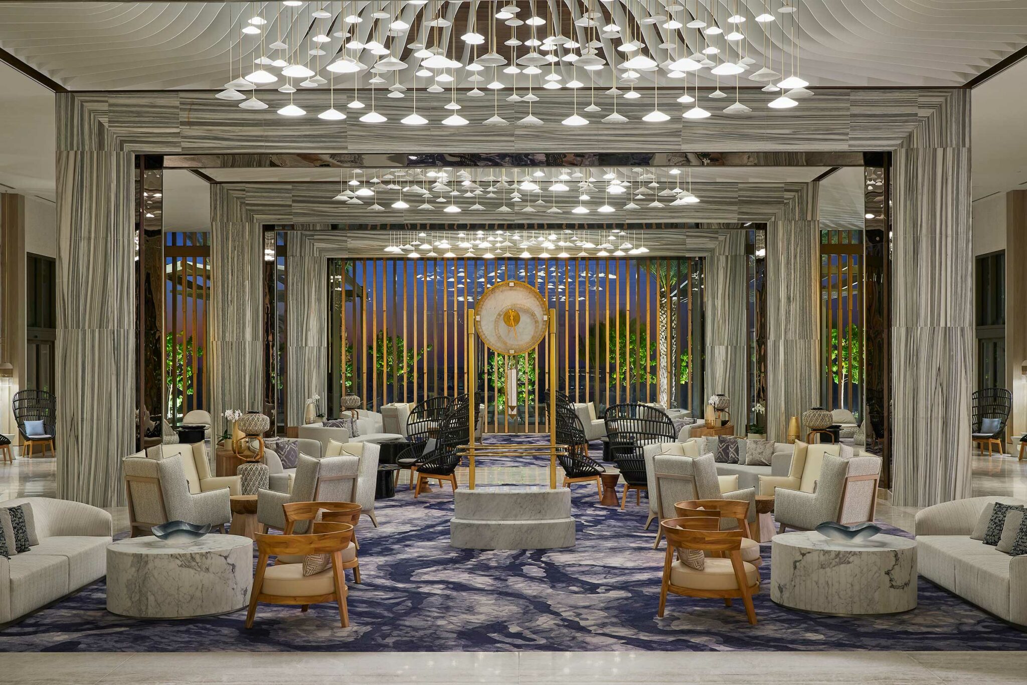 Modern resort lounge with elegant decor features marble accents, contemporary seating, and ambient lighting. A central artistic sculpture anchors the space.