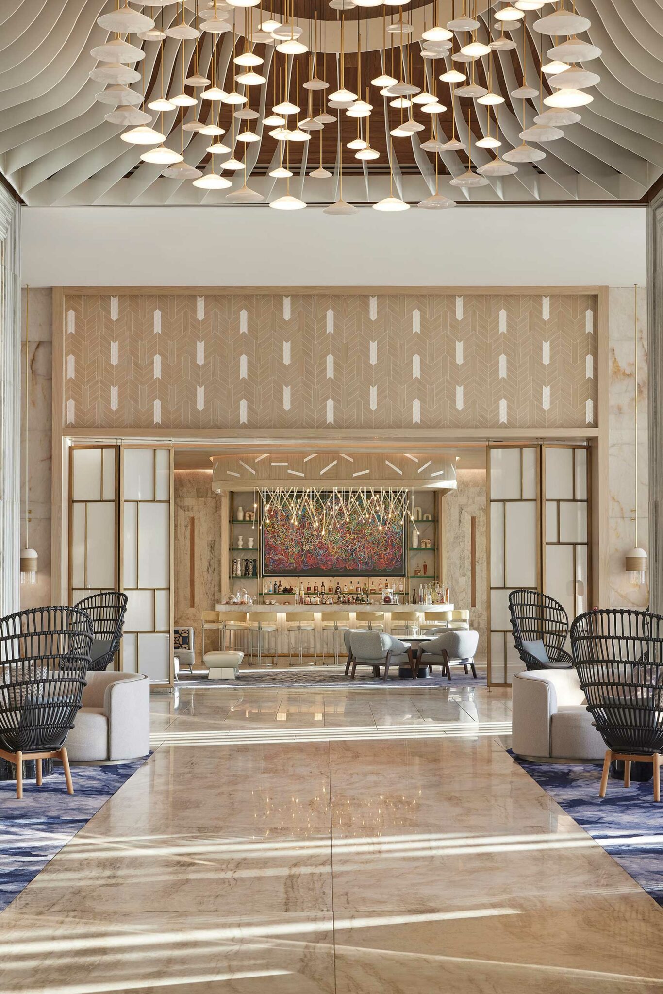 Luxurious resort lobby featuring plush seating, a stylish bar, and a colorful abstract art piece. A chic chandelier hangs from the ceiling, exuding elegance.