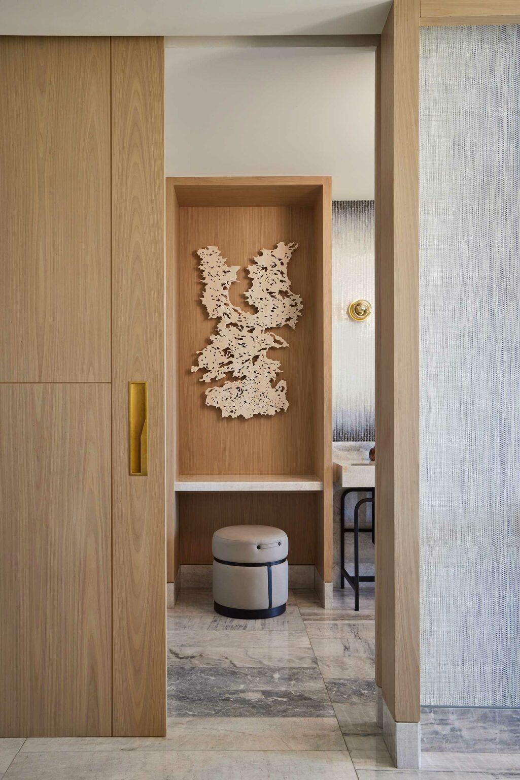 Wall-mounted abstract art above a minimalist vanity in a modern suite bathroom. Features wood elements, marble surfaces, and warm tones, conveying a serene ambiance.