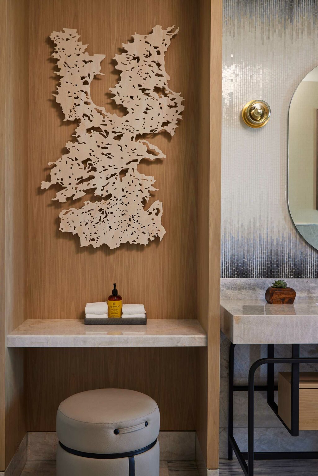 Wall-mounted abstract art above a minimalist vanity in a modern suite bathroom. Features wood elements, marble surfaces, and warm tones, conveying a serene ambiance.