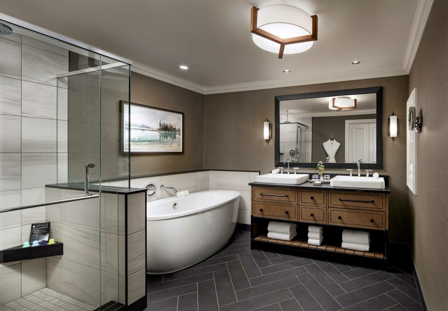 Luxurious suite bathroom with a glass shower, freestanding tub, double sink vanity, and large mirror. Soft lighting and earth tones create a relaxing ambiance.