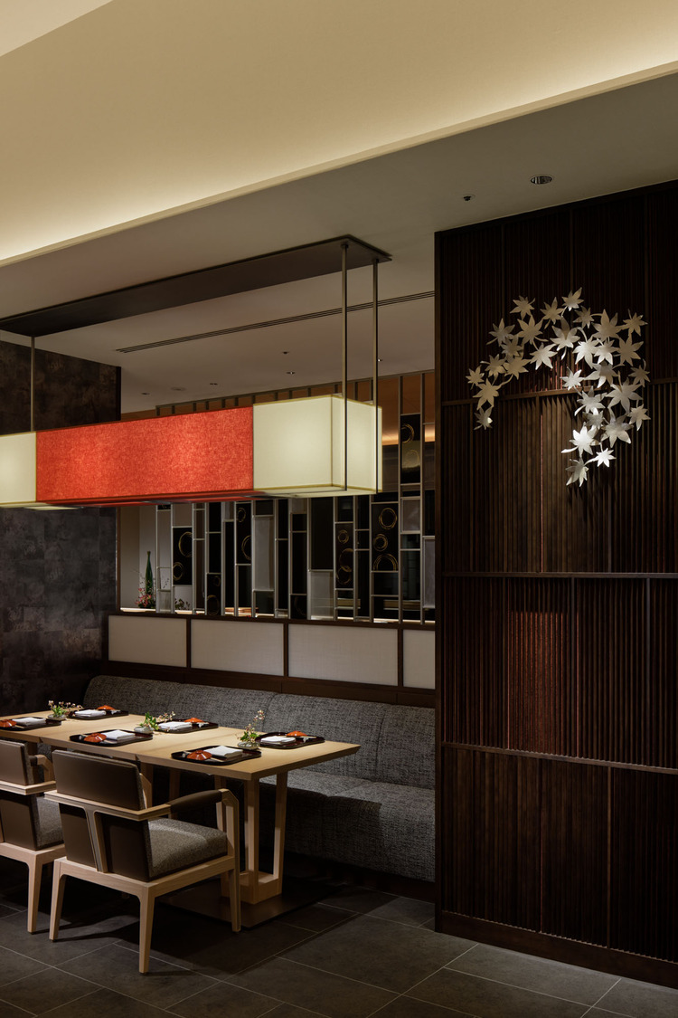 Elegant hotel lounge with dim lighting, featuring round tables, plush chairs, and a sleek bar in the background. The ambiance is cozy and sophisticated.