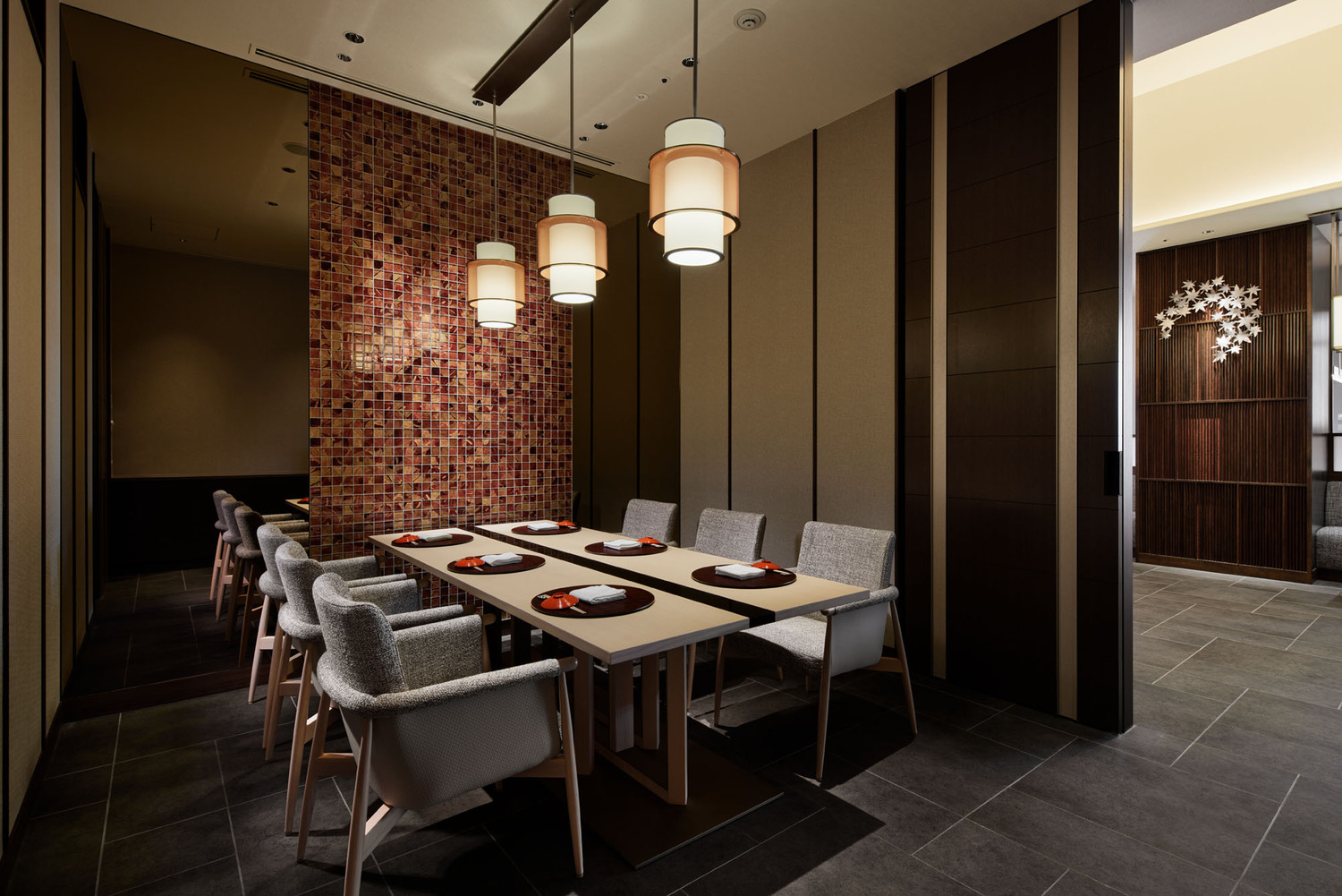 Elegant hotel lounge with dim lighting, featuring round tables, plush chairs, and a sleek bar in the background. The ambiance is cozy and sophisticated.