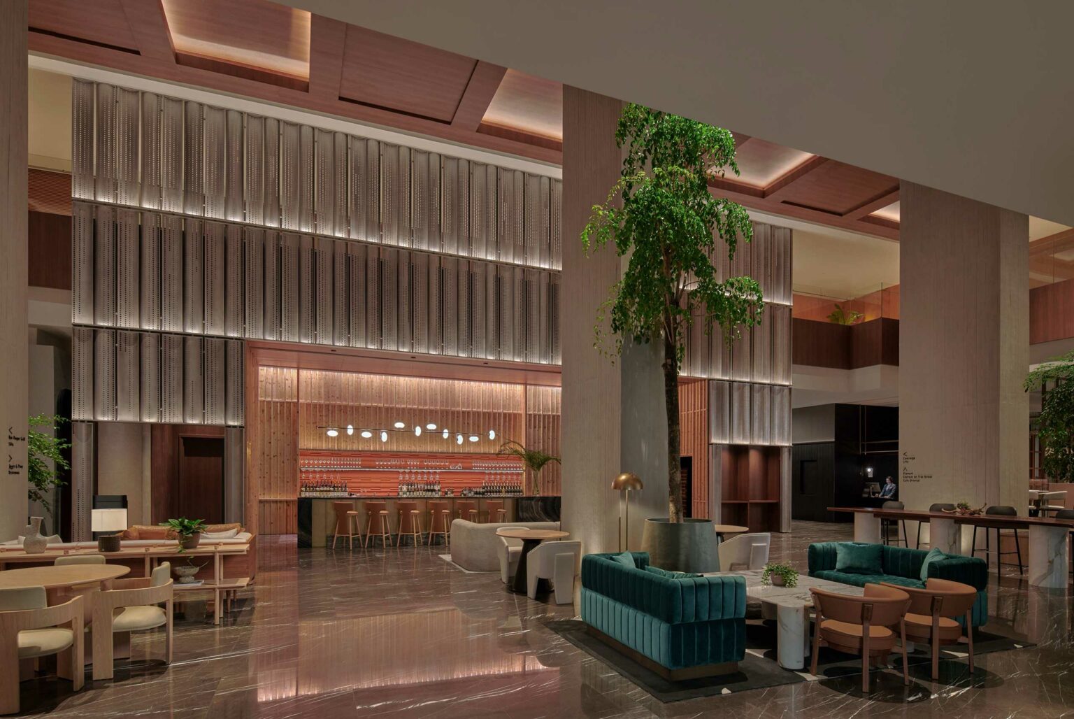 Luxurious hotel lobby with modern design, featuring high ceilings, plush seating, a central large plant, and a stylish bar at the back. Warm, inviting ambiance.