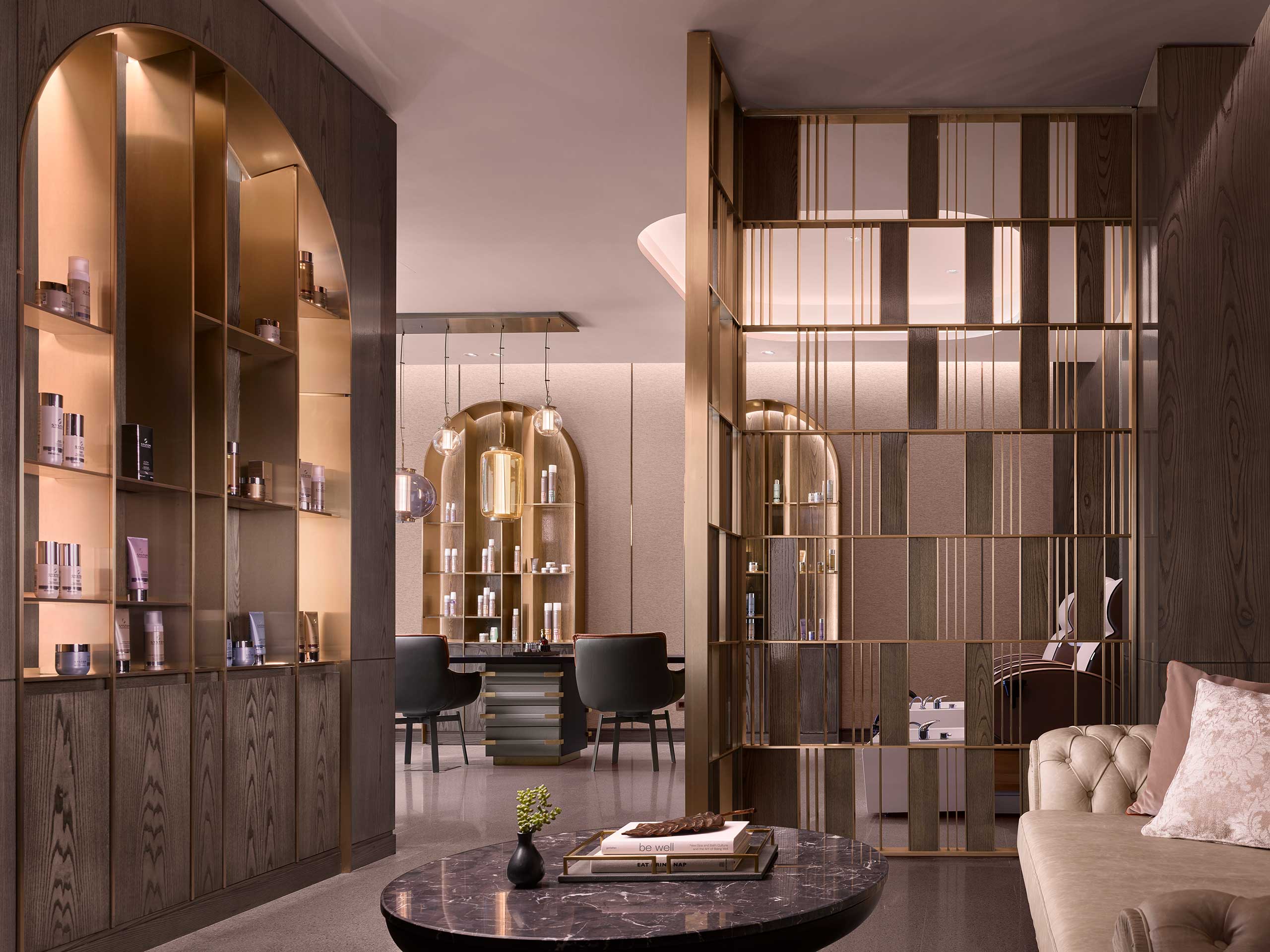 Luxurious spa interior with warm lighting, wooden shelves displaying products, a round marble table, and modern chairs, conveying elegance and tranquility.