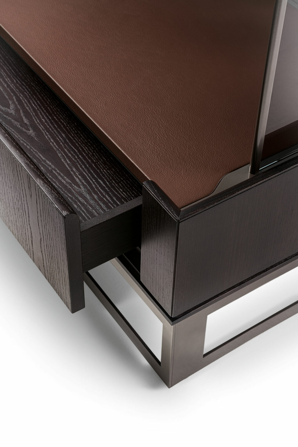 Close-up of a sleek, modern sideboard with dark wood finish and a brown leather top. The design includes a partially open drawer and metal base. Elegant and minimalist.