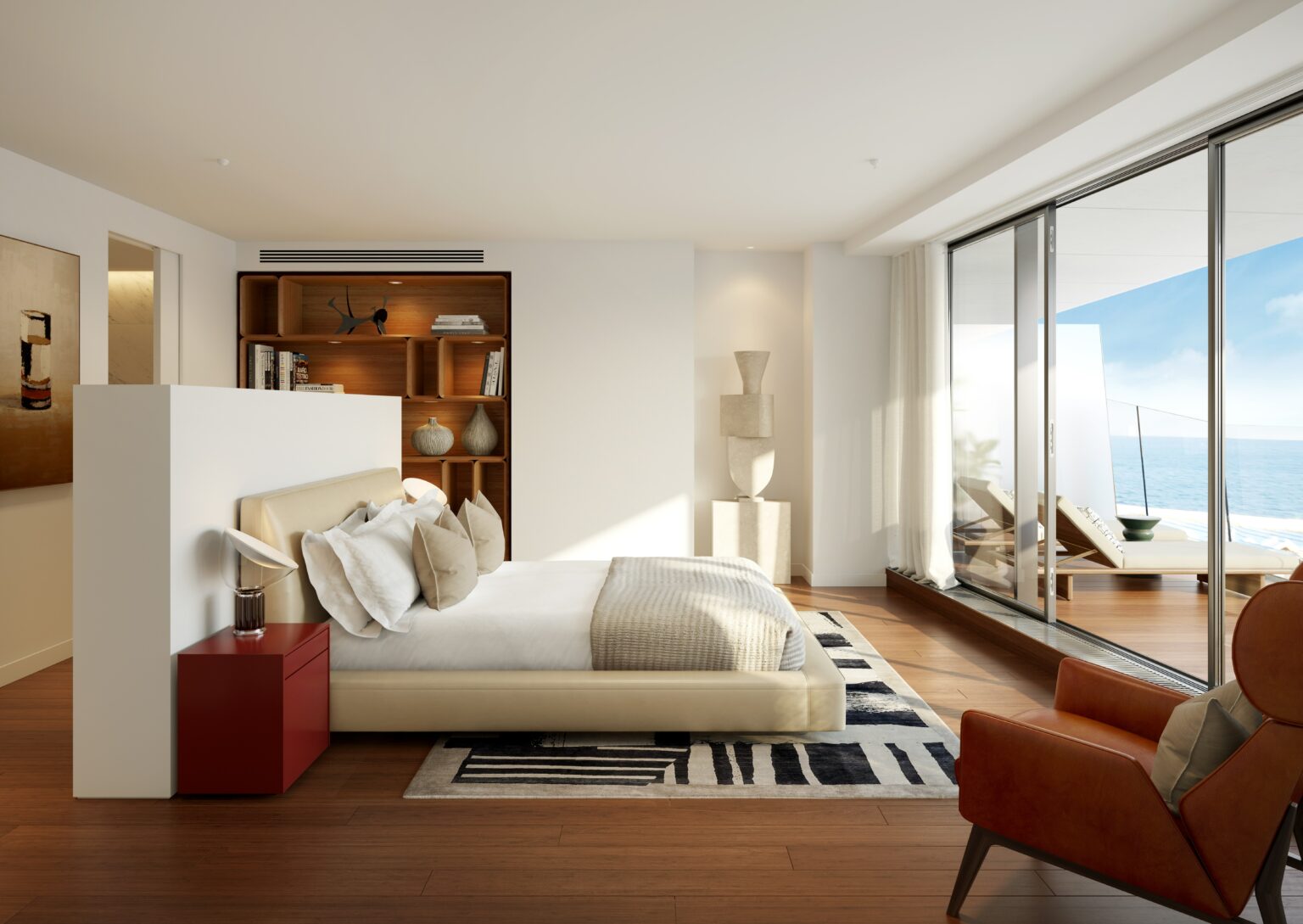 Modern bedroom with a beige bed, red side table, and decorative pillows. Sunlit ocean view through glass doors. Warm, inviting atmosphere.