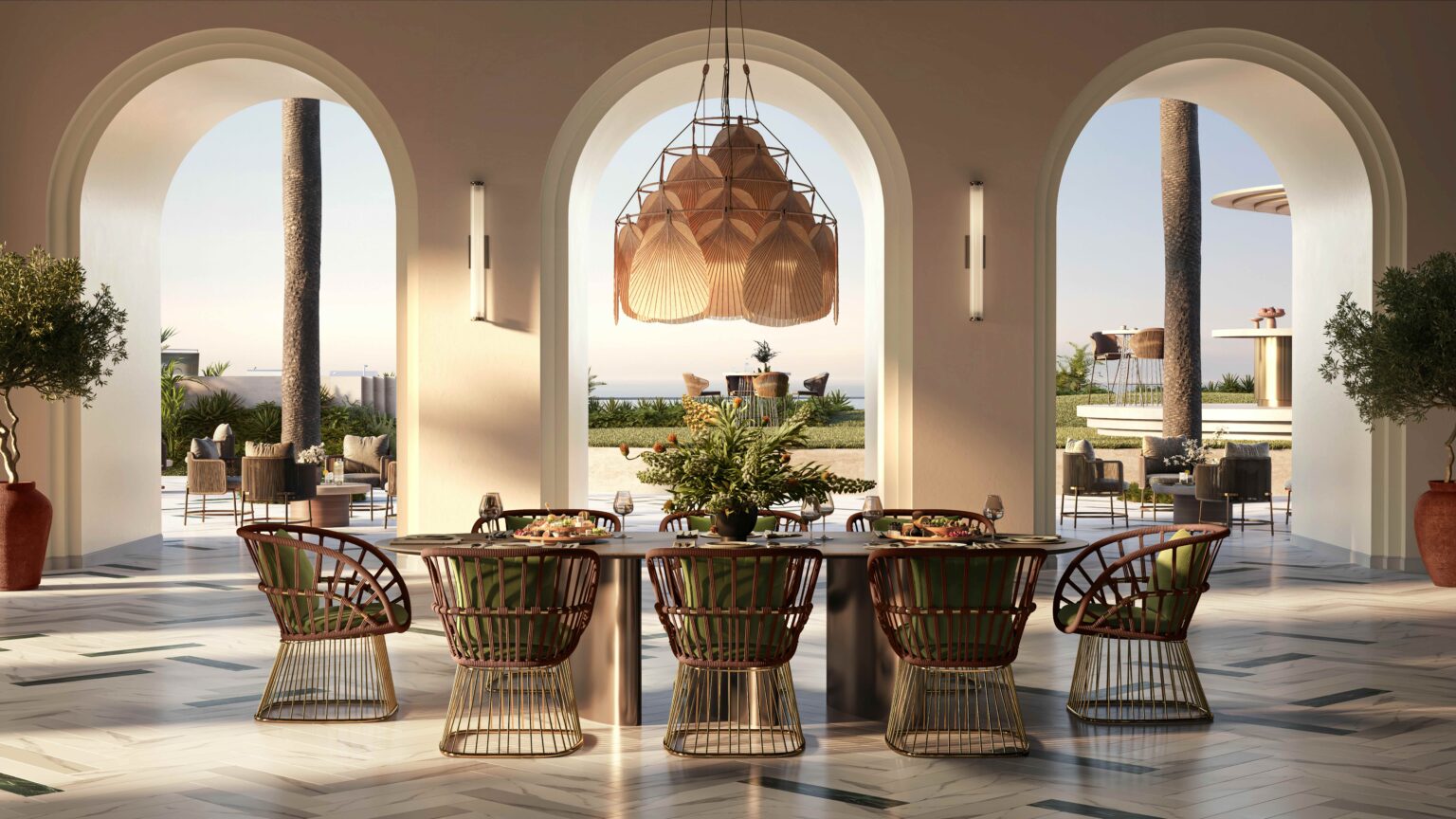 Elegant dining area with wicker chairs and a large table, under a woven chandelier. Arched windows reveal a sunny patio and ocean view. Relaxed, coastal vibe.
