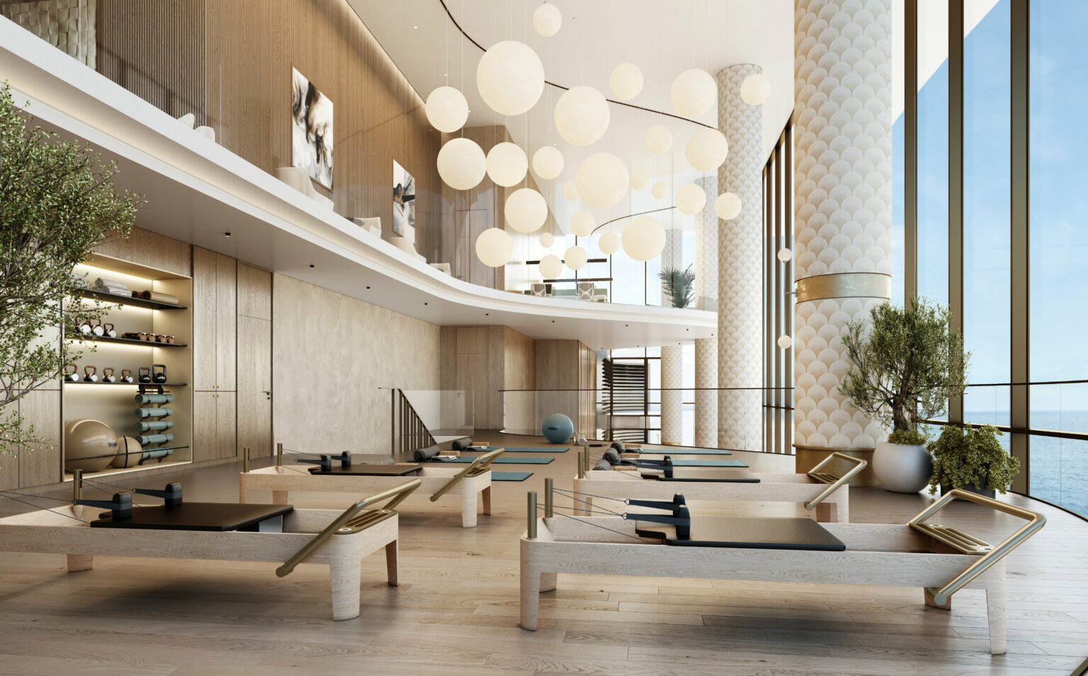 Luxurious, modern Pilates studio with wooden equipment, large windows showcasing ocean views, and elegant globe lights above, creating a serene atmosphere.
