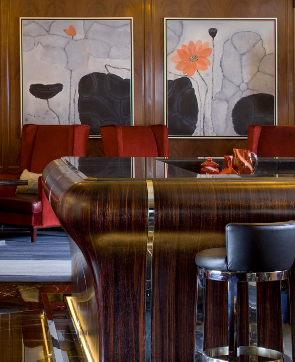 Luxurious jazz bar counter with wooden panels and chrome accents. Red chairs face abstract floral paintings, creating a sophisticated, elegant atmosphere.