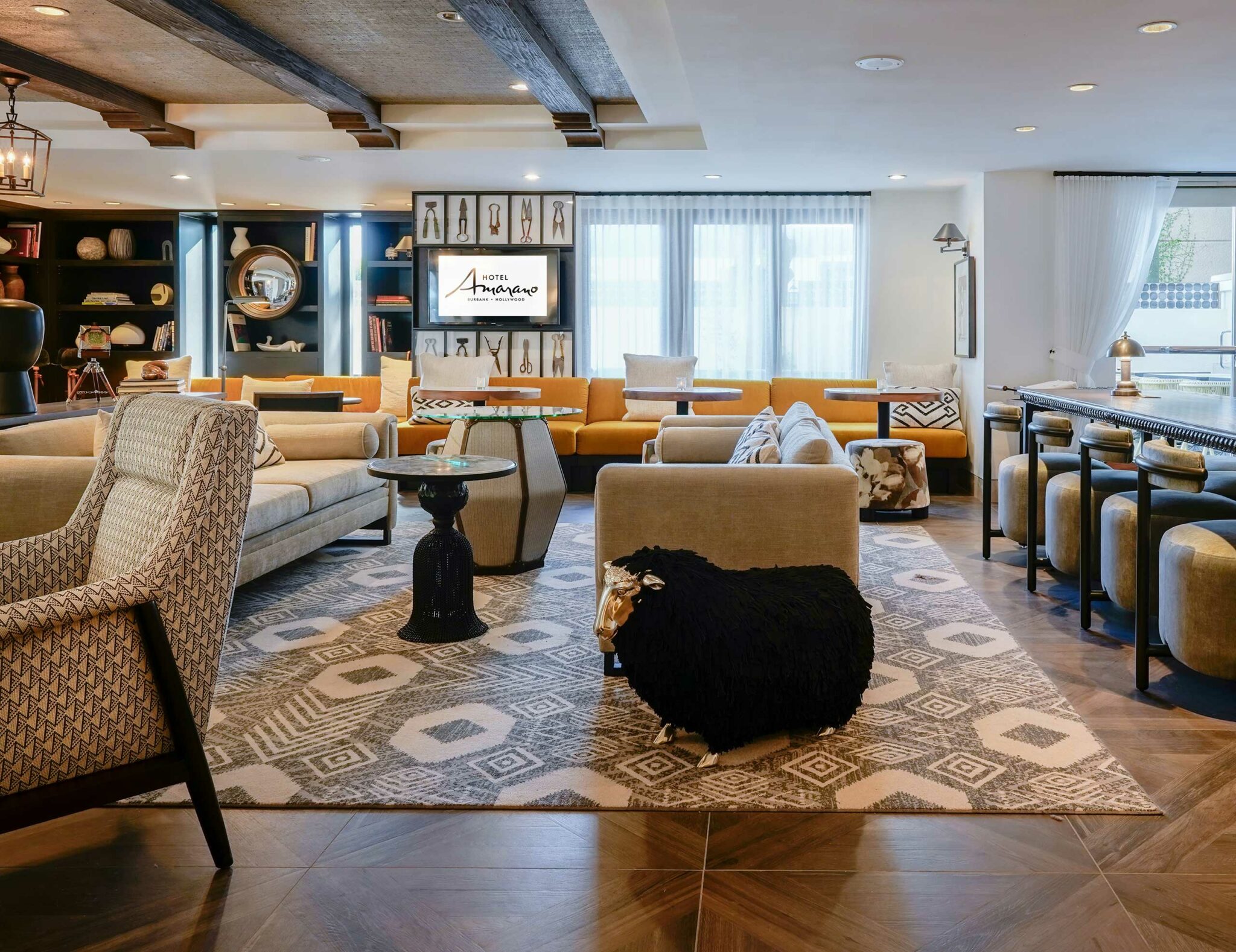 Stylish hotel lounge with geometric carpet, plush seating, modern decor, and a playful black sheep sculpture, creating a chic and inviting atmosphere.