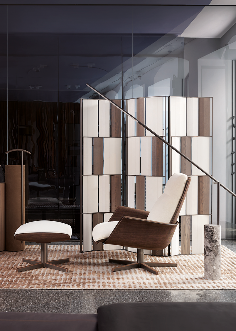 Elegant modern living room featuring a white and brown armchair with matching ottoman on a patterned rug. A three-panel room divider with vertical beige and brown panels arranged in an alternating pattern adds style. Its metal frame gives an extra touch of modern, elegant look.