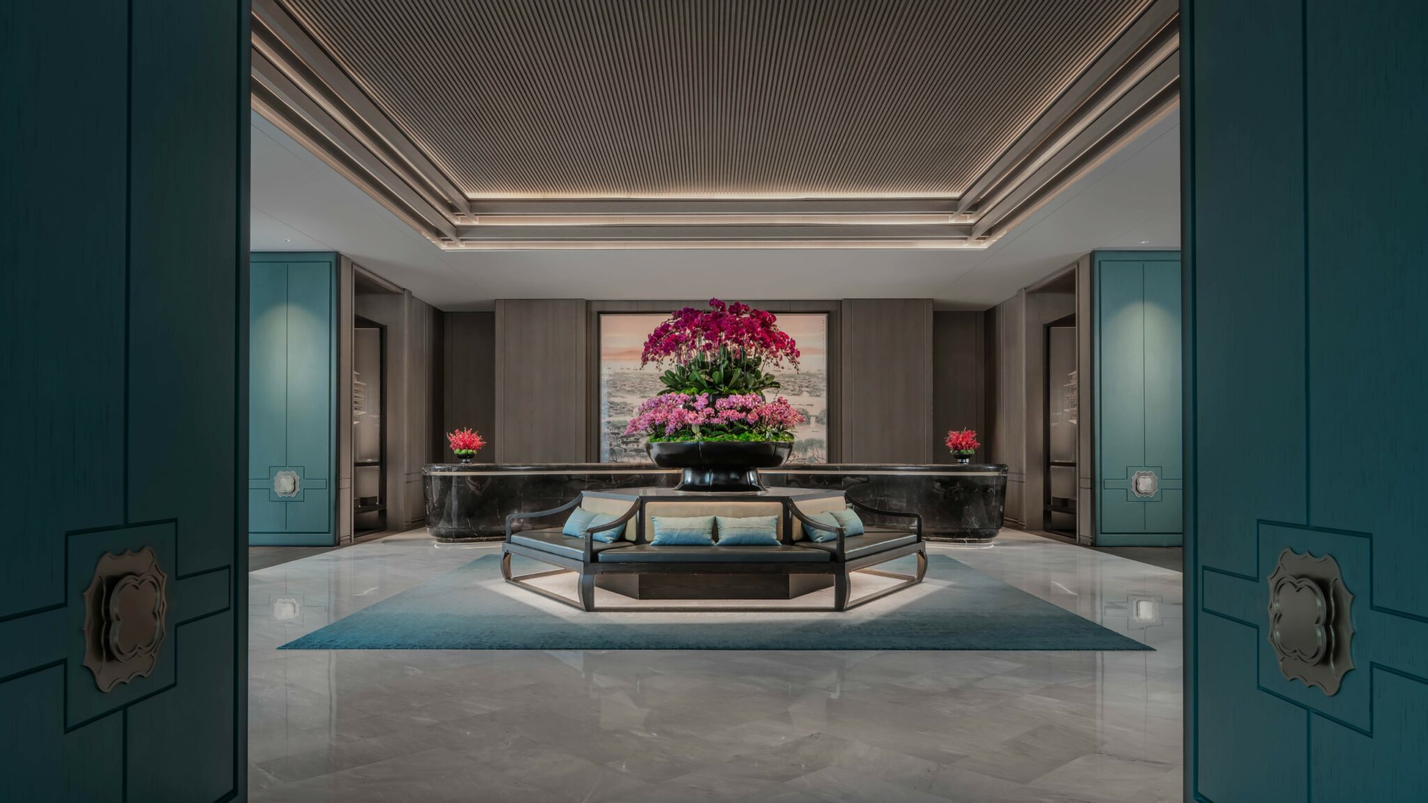 Elegant hotel lobby with a central floral arrangement of pink orchids atop a circular bench. Modern decor, teal accents, and a calm, luxurious ambiance.