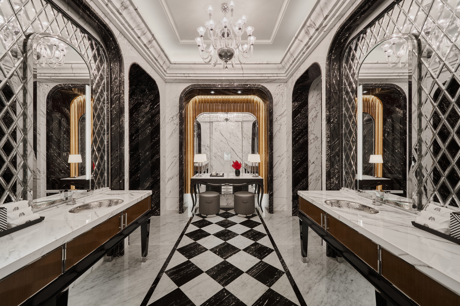 Luxurious hotel restroom with black and white marble walls and floor, featuring geometric patterns. Elegant chandeliers enhance the opulent, sophisticated atmosphere.